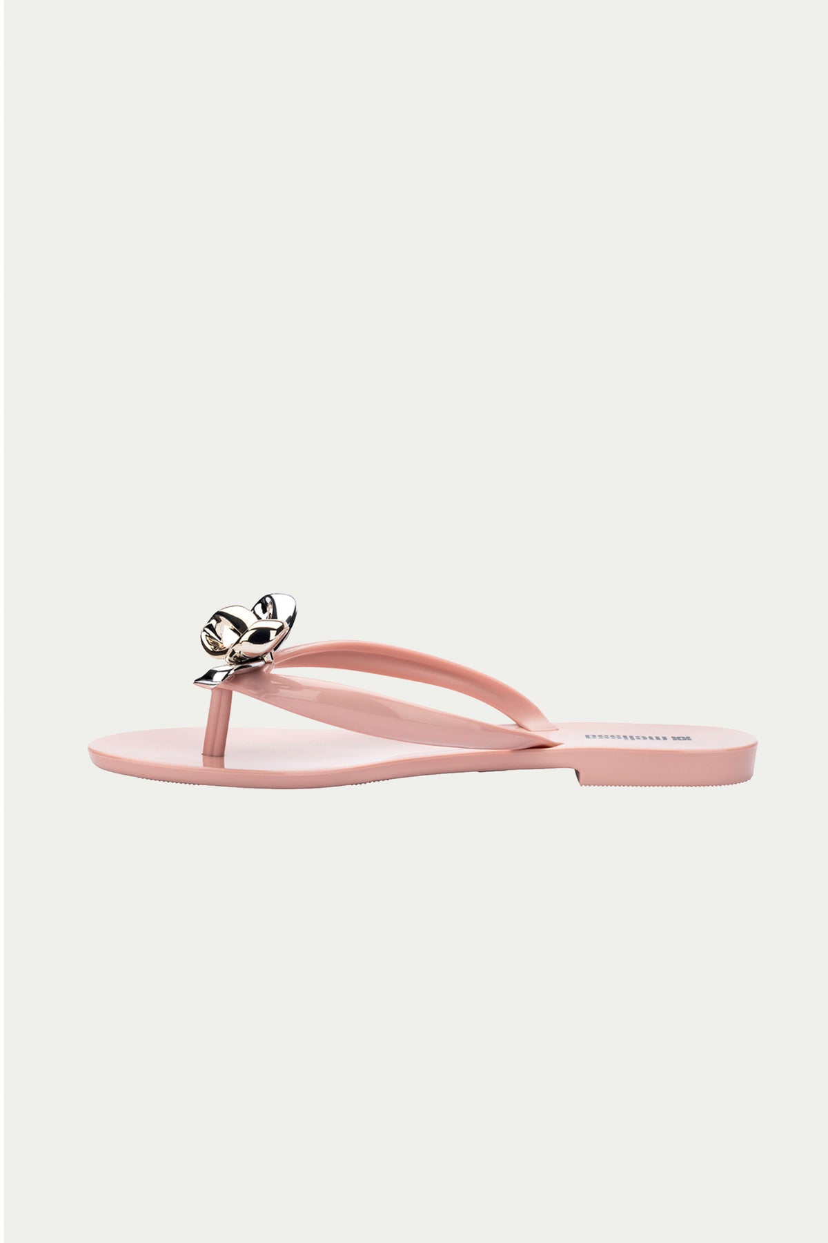 The Melissa Harmonic Eclipse Bow Sandal in pink features a thong strap with a metallic silver floral accent, shown against a plain light background.