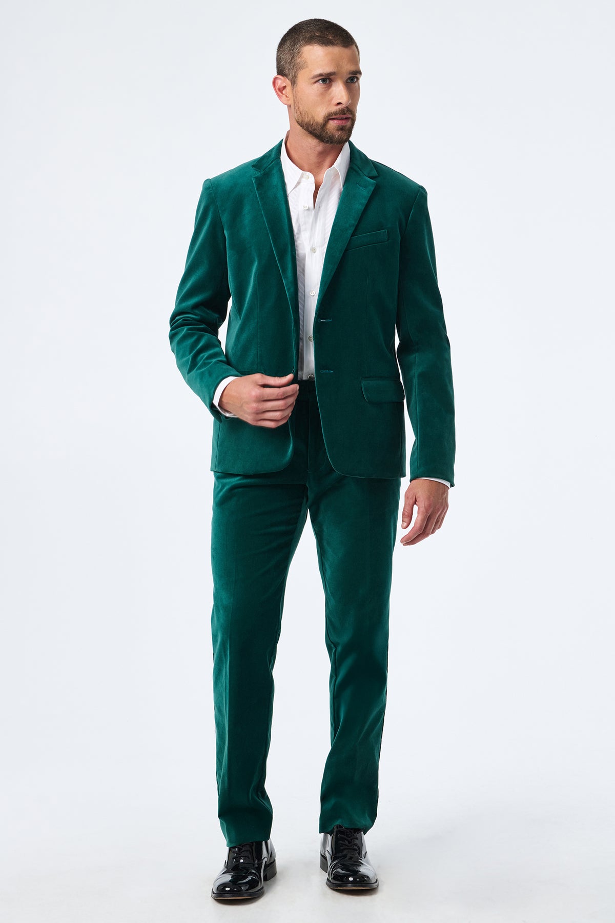 A man with short dark hair and a beard wears the Thurston Velvet Blazer over a white dress shirt and black dress shoes, standing against a plain white background.