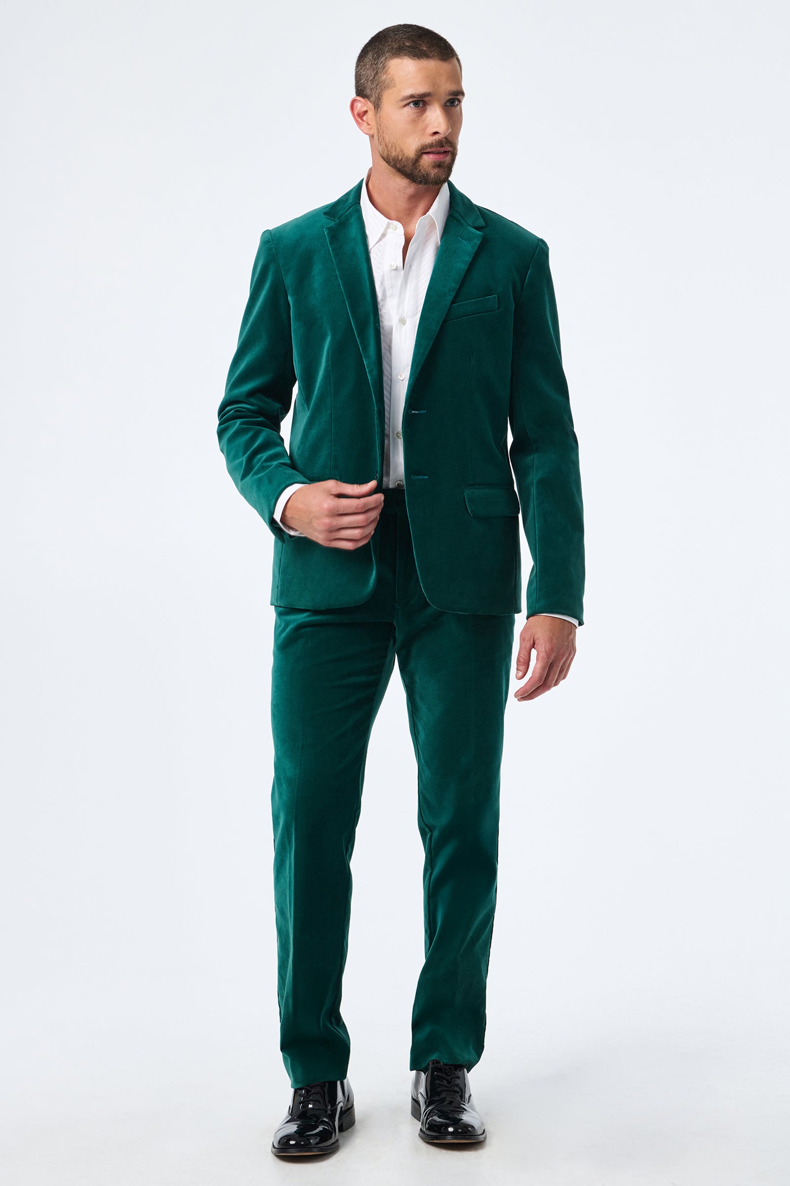 A man with short dark hair and a beard wears the Thurston Velvet Blazer over a white dress shirt and black dress shoes, standing against a plain white background.