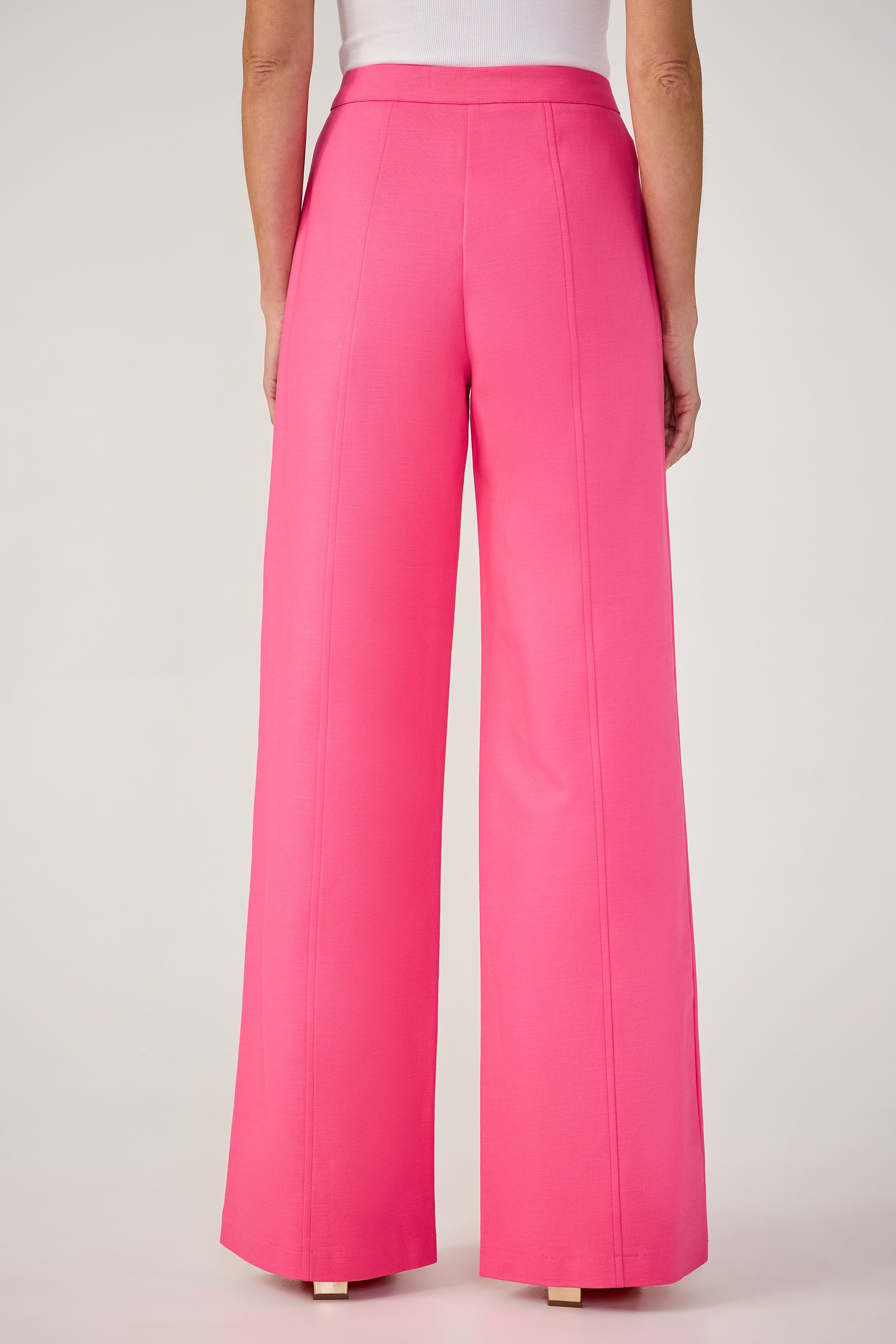 A person shown from the back wears the Half Court Wide-Leg Pant - Solid Suiting in pink, featuring a high-waisted, tailored fit with visible seam details, paired with a white top.