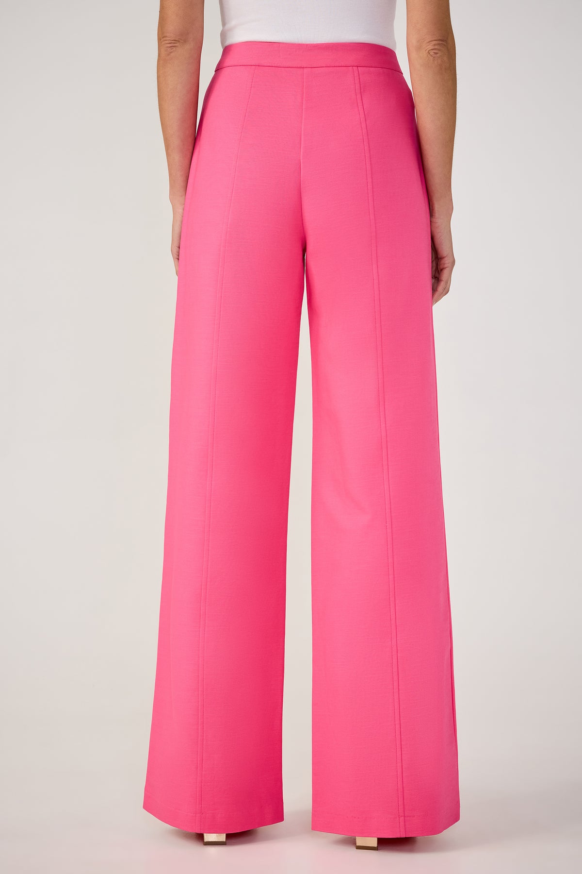 A person shown from the back wears the Half Court Wide-Leg Pant - Solid Suiting in pink, featuring a high-waisted, tailored fit with visible seam details, paired with a white top.