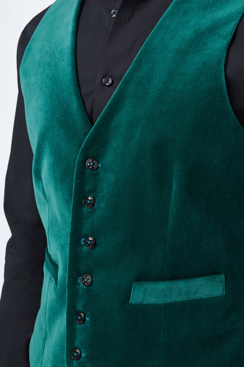 A close-up of a person wearing the Irving Vest in deep green velvet over a black dress shirt, featuring black buttons and a welt pocket.