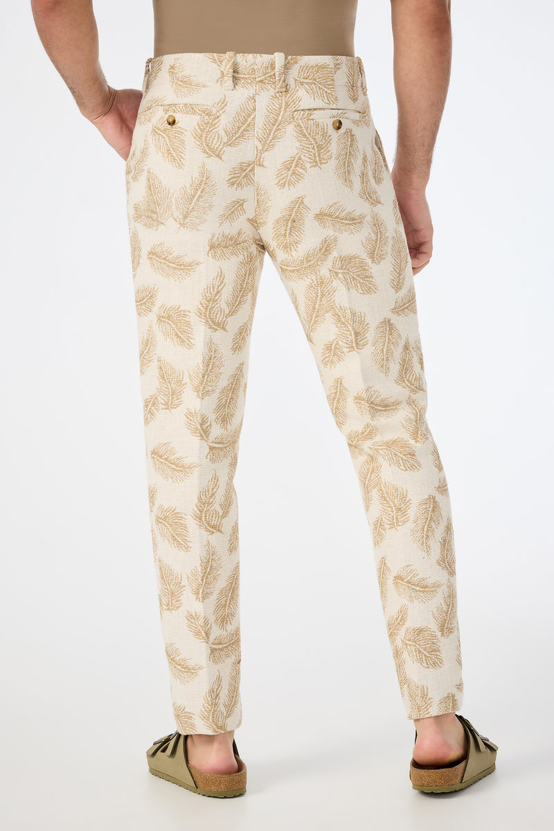 A person stands facing away, wearing the Alex Slim Trouser in Desert Fronds Jacquard with a tan shirt tucked in and tan suede moccasins, set against a plain white background.