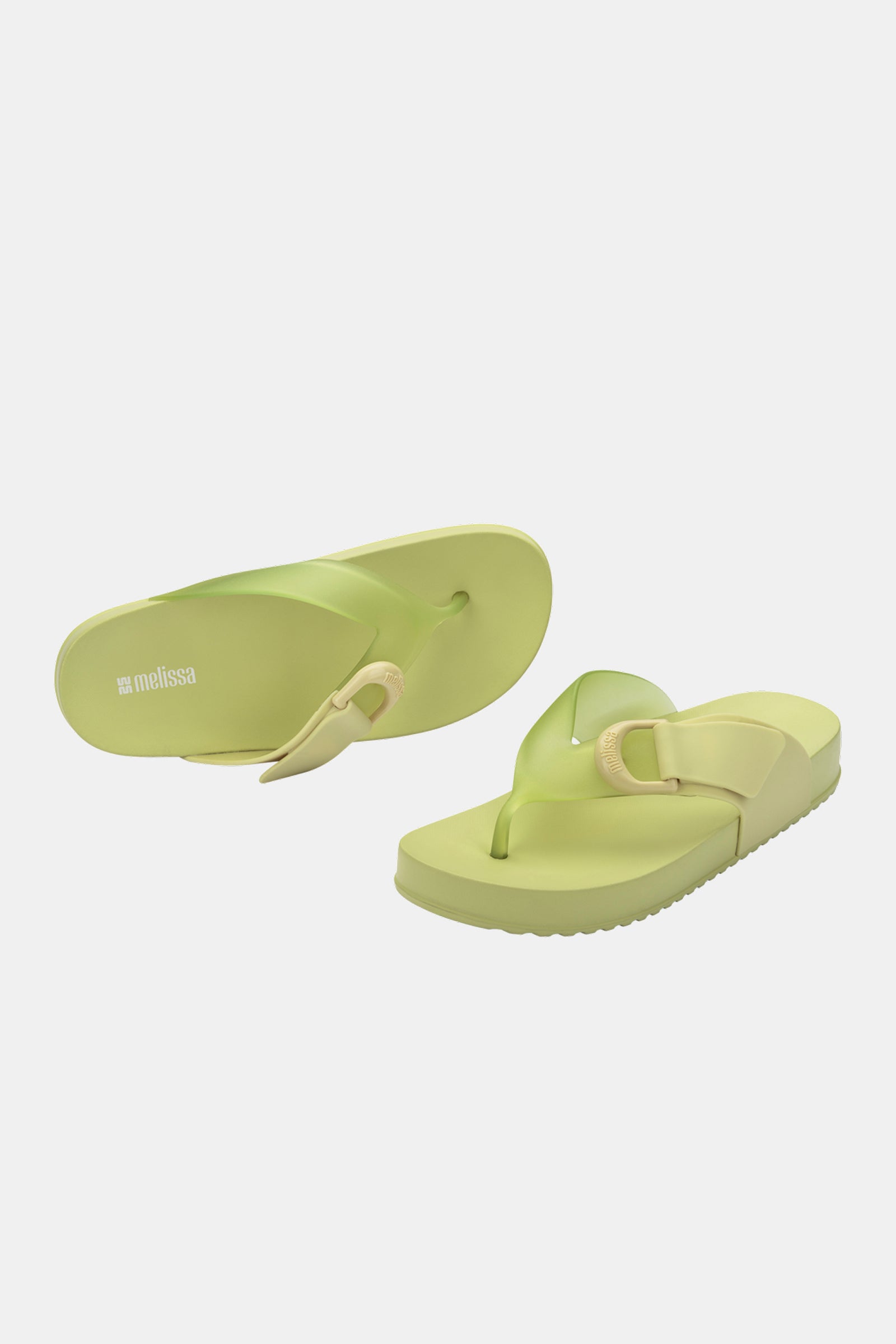 The Melissa Cozy Thong sandals in light green feature thick soles and wide straps. Displayed on a plain white background, one lies flat while the other is propped up, showcasing both side and top views.