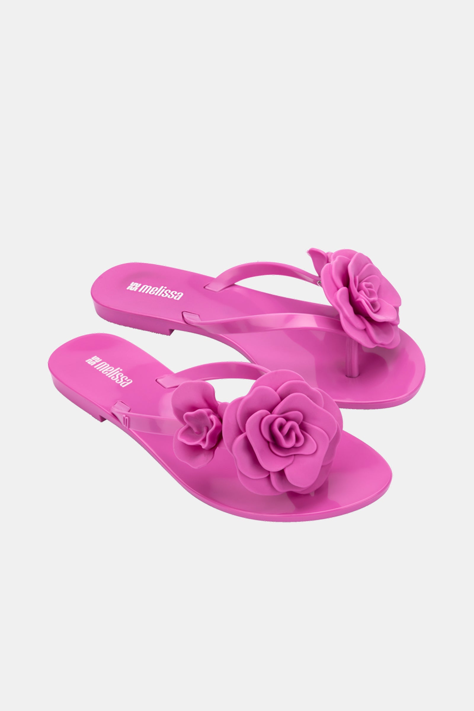 A pair of Melissa Harmonic Petals Sandals in bright pink, featuring large rose-shaped flowers on the straps, displayed against a plain white background.