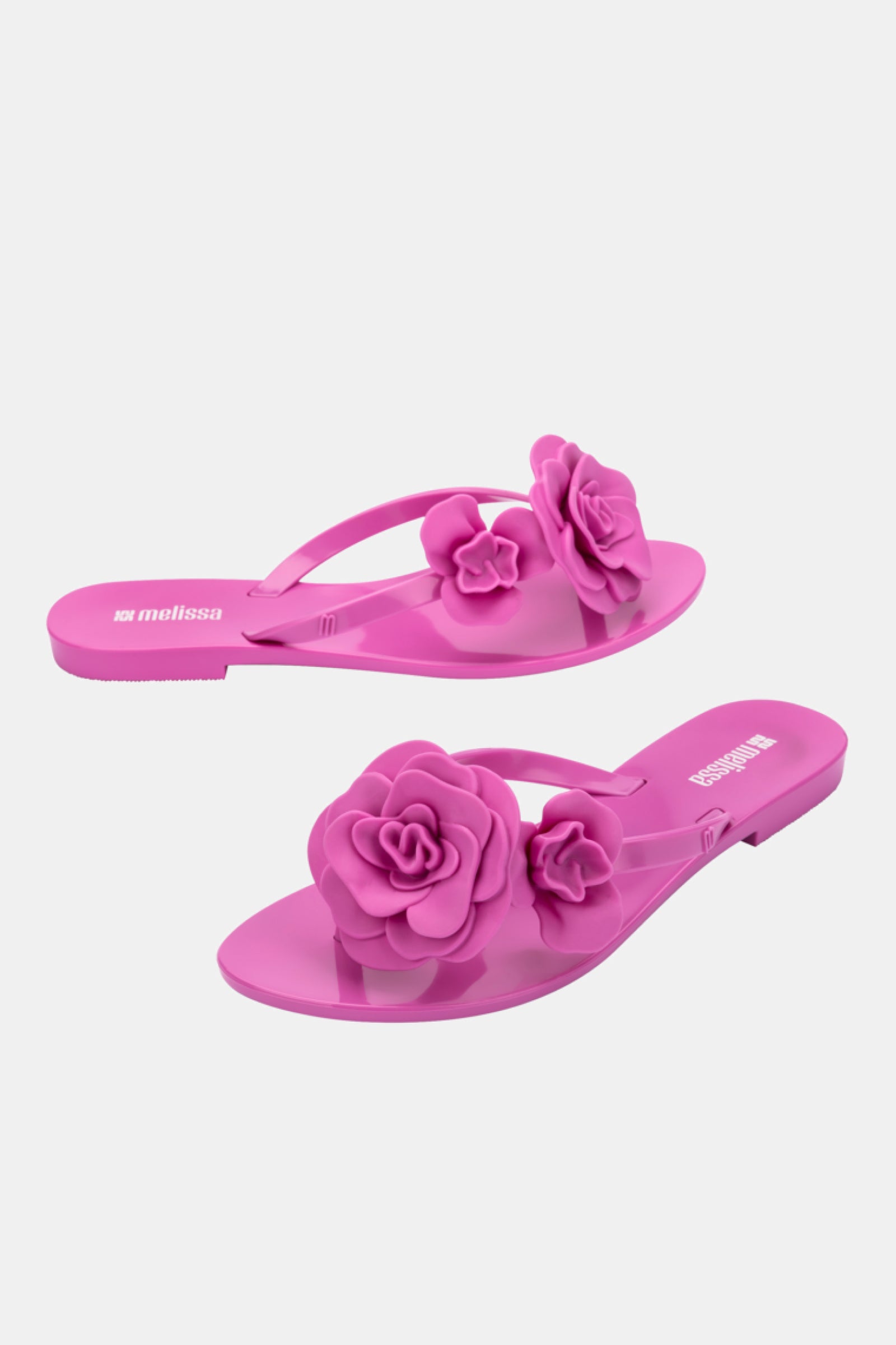 The Melissa Harmonic Petals Sandal is a pair of bright pink flip-flops with bold 3D flower decorations on the straps, shown against a plain white background.