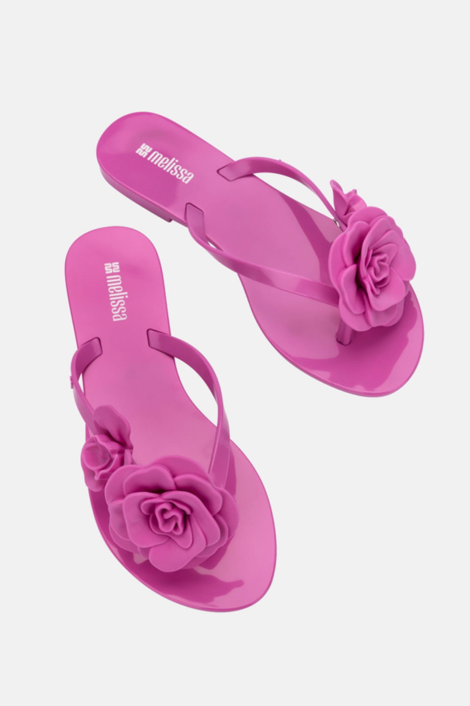 The Melissa Harmonic Petals Sandal is a bright pink flip-flop featuring large decorative flower accents on the straps, shown against a light background.