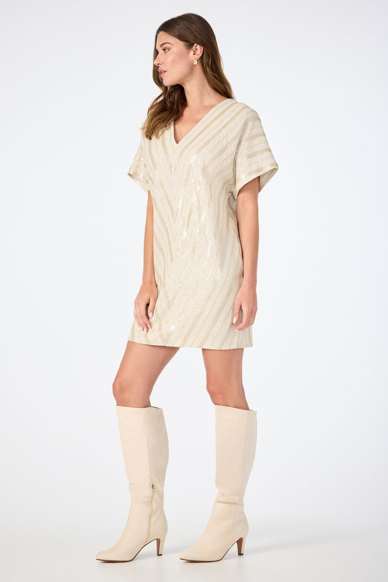 A woman wears the TRINA TURK Elisabetta Short-Sleeve Dress and knee-high light beige heeled boots, standing against a plain white background.