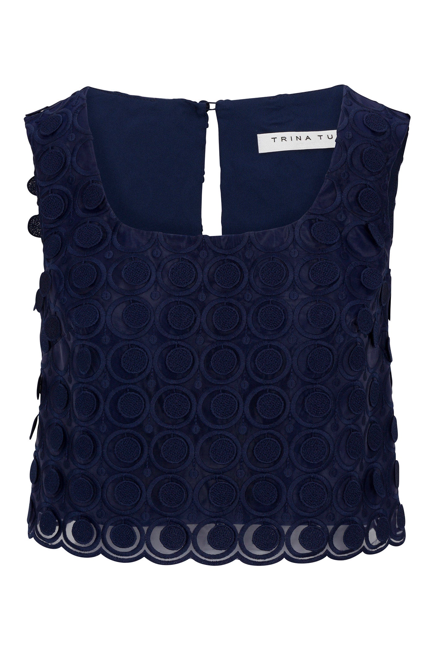 The Serve Sleeveless Top - Agassi Embroidery is a navy blue, sleeveless style with a round neckline, sheer overlay with circular textured embroidery, and a small button closure at the back.
