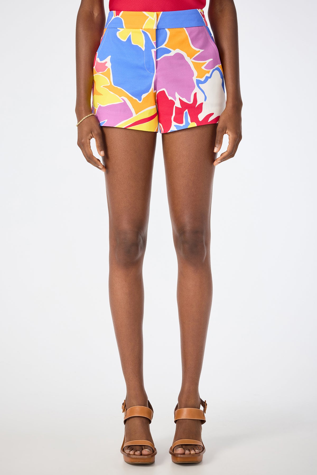 A person models the Corbin 2 Shorts in Soie Paradis—colorful, high-waisted floral shorts—paired with brown heeled sandals, against a plain white background. The image is cropped from waist to feet.