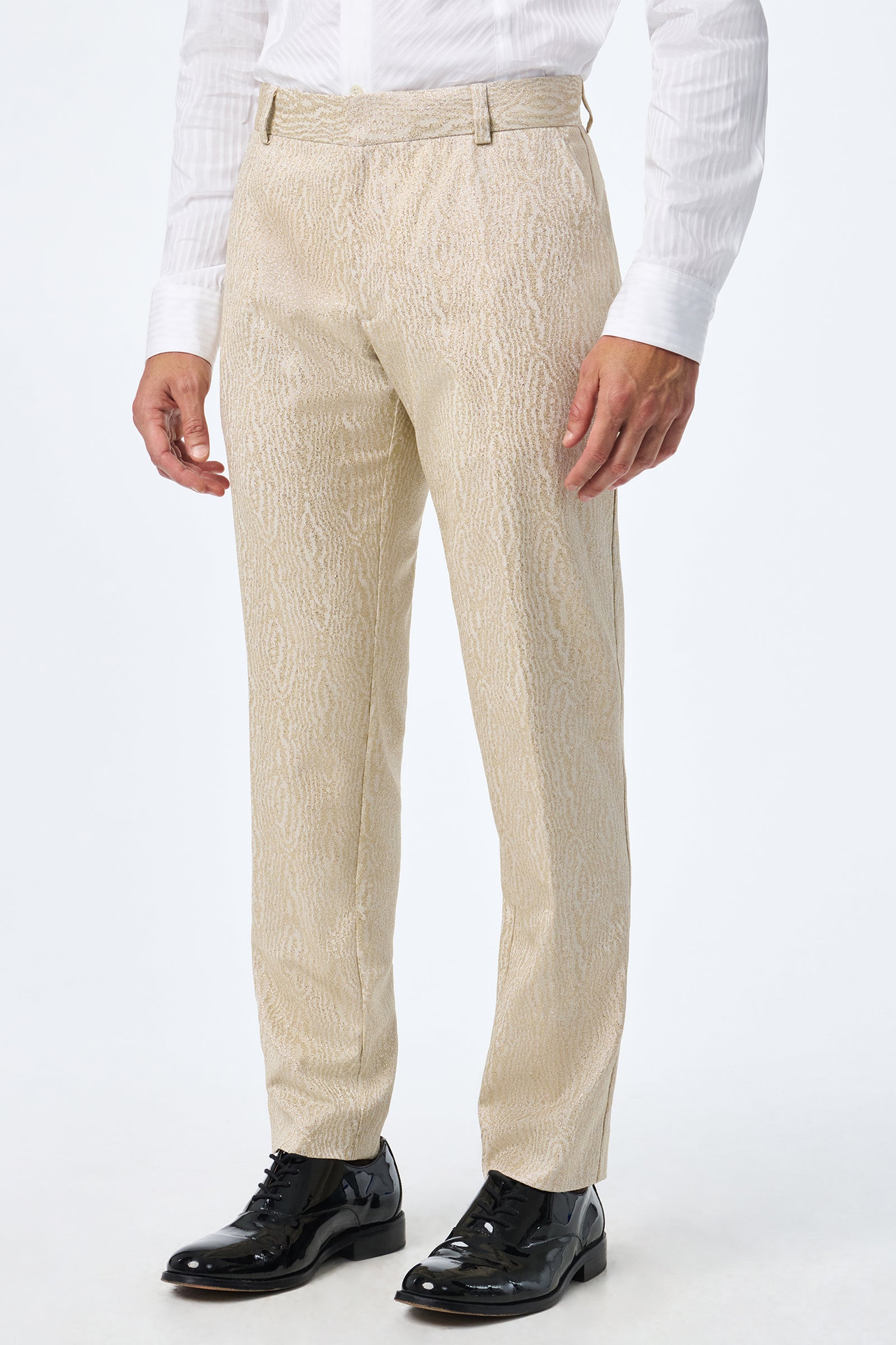 A person wearing the Clyde Slim Trouser in textured light beige, paired with a white dress shirt and shiny black dress shoes, stands against a plain white background.