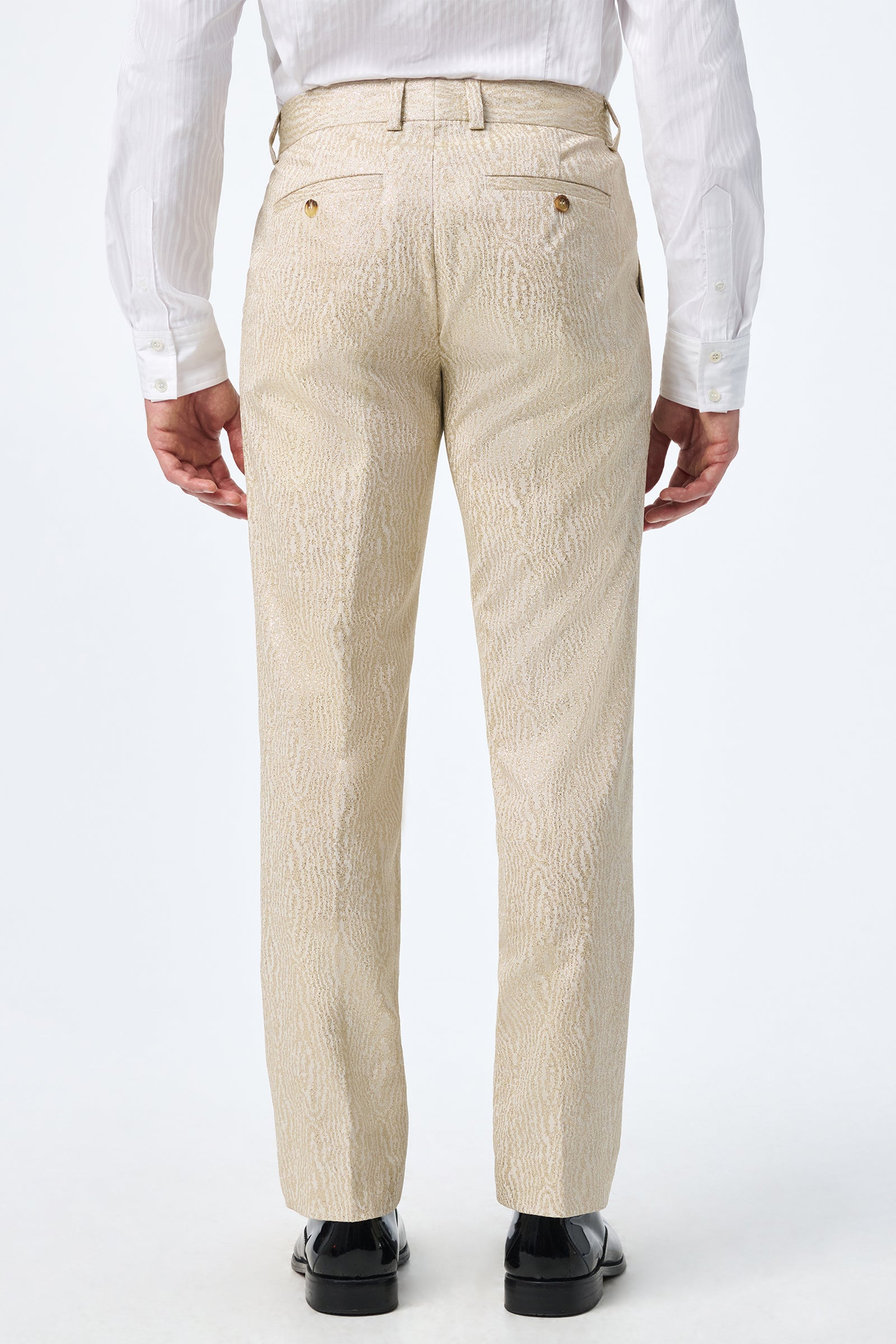 A person is seen from behind, wearing Clyde Slim Trouser in light beige with a white long-sleeve dress shirt and black dress shoes, standing against a plain white background.