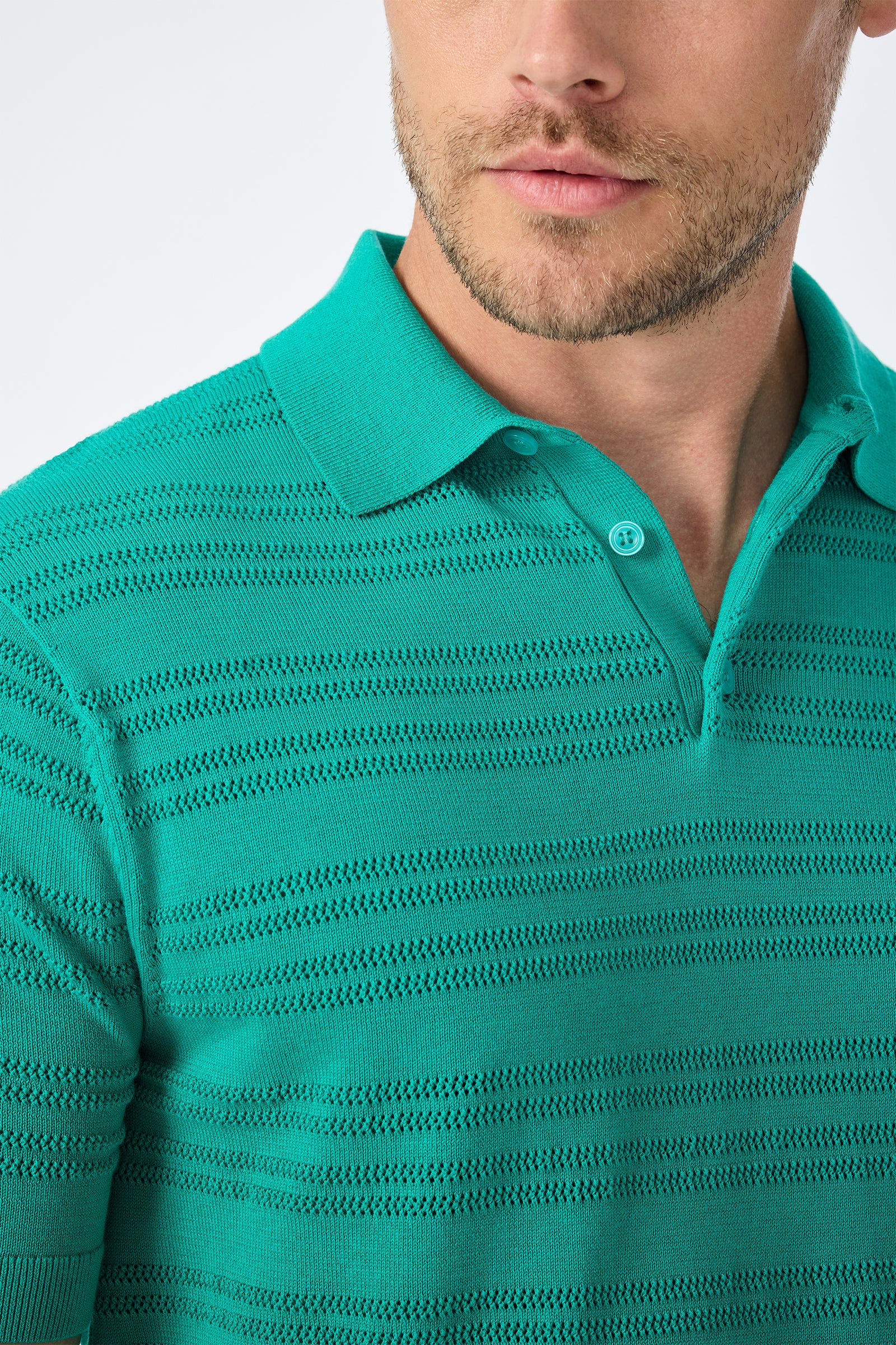 A man wearing the Edison Short-Sleeve Striped Polo in green, featuring subtle horizontal patterns. Only his lower face, neck, and upper torso are visible.