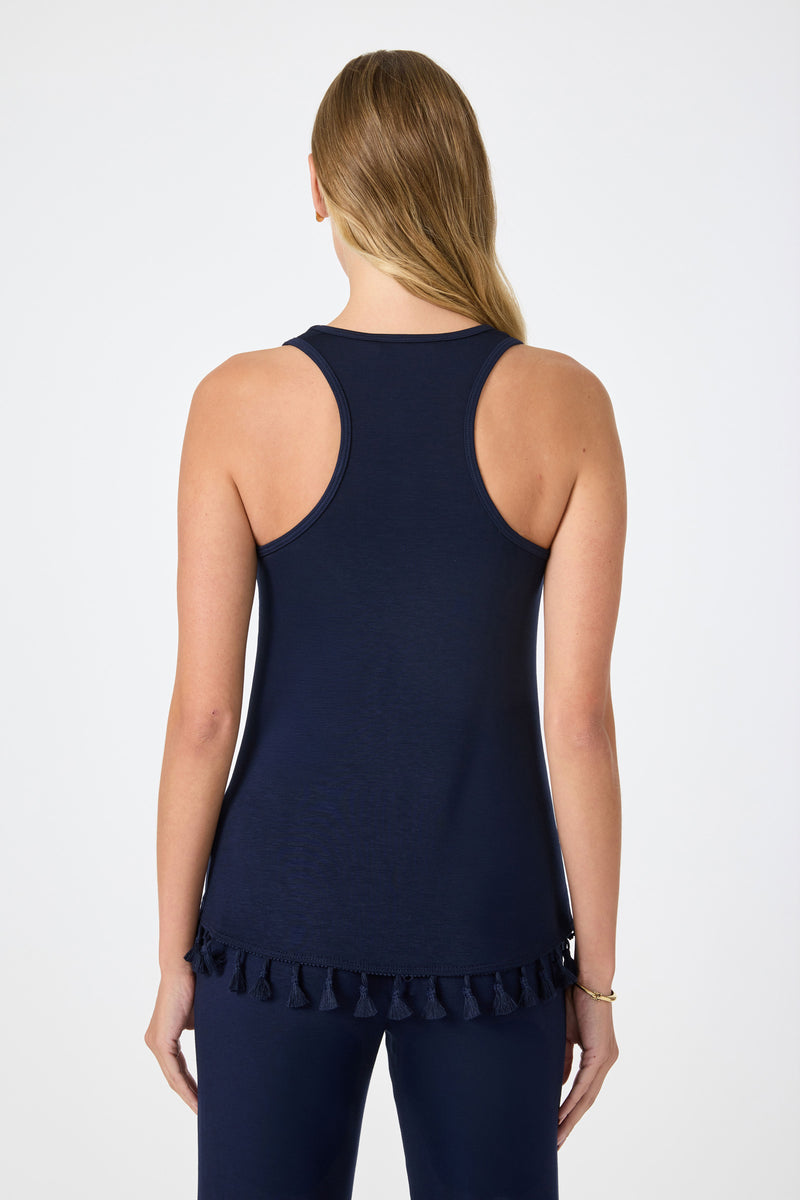 A woman with long, straight blonde hair stands with her back to the camera, wearing the Tajo 2 Tassel Hem Sleeveless Top in navy blue and matching navy pants against a plain light background.