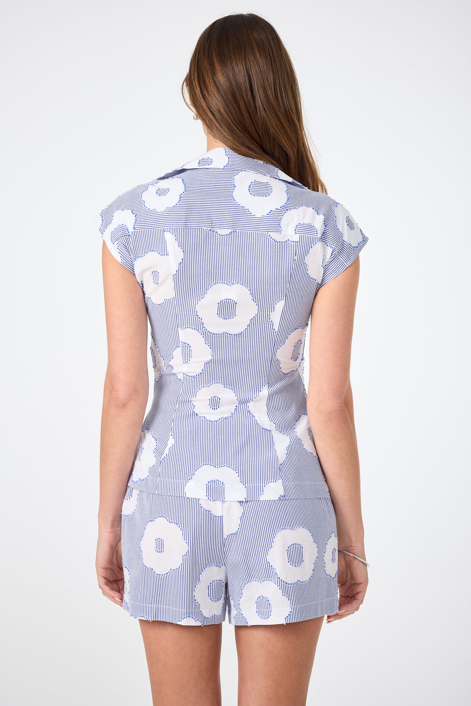 A woman with long brown hair, seen from behind, wears the Avant Top - Cassis Cotton against a plain, light background.