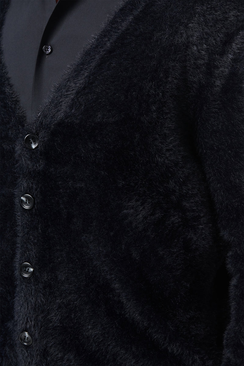 Close-up of a person wearing the Scott Fuzzy Cardigan in black over a black collared shirt. The cardigan has a soft, plush texture and features four visible buttons.