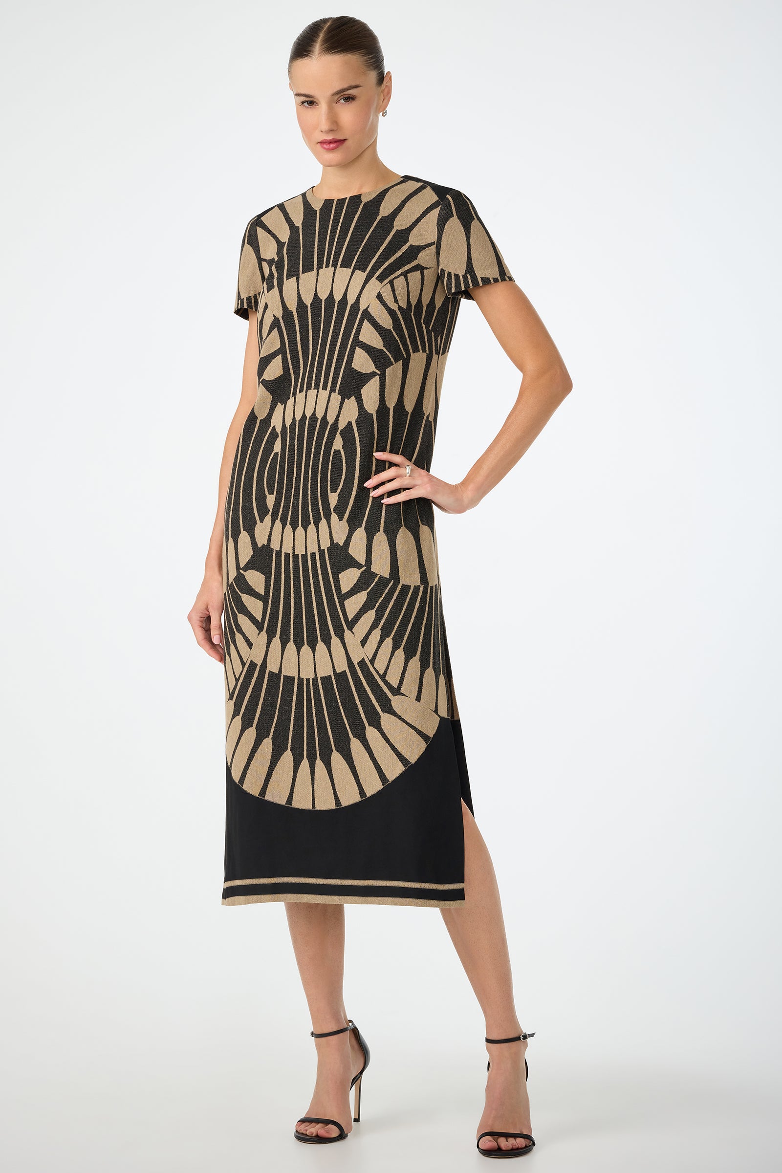 Woman wearing the Sugarita Midi Dress in Juniper Fil Coupe, featuring short sleeves and geometric patterns, standing with one hand on her hip and paired with black high-heeled sandals.