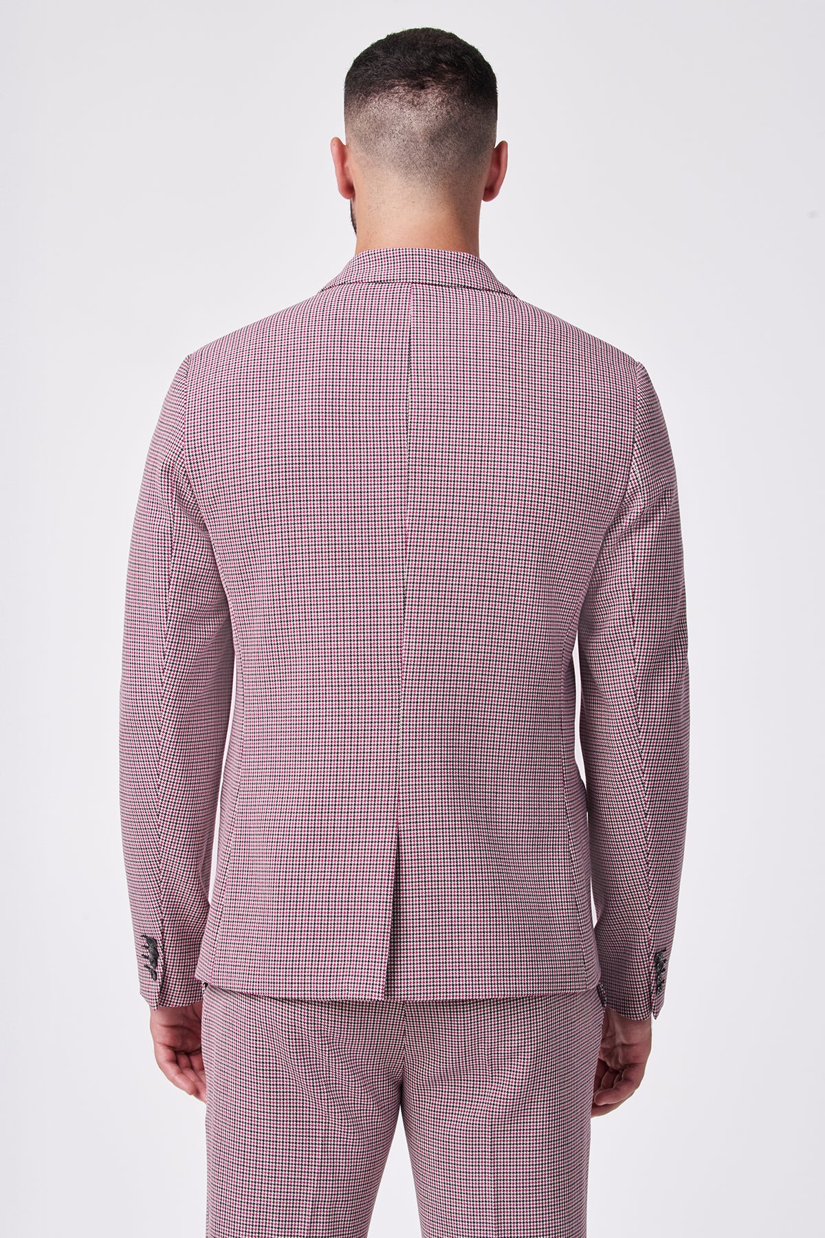 A man faces away from the camera in a fitted THURSTON BLAZER, a pink and white checkered suit made from a soft viscose blend with added elastane stretch, set against a plain white background.