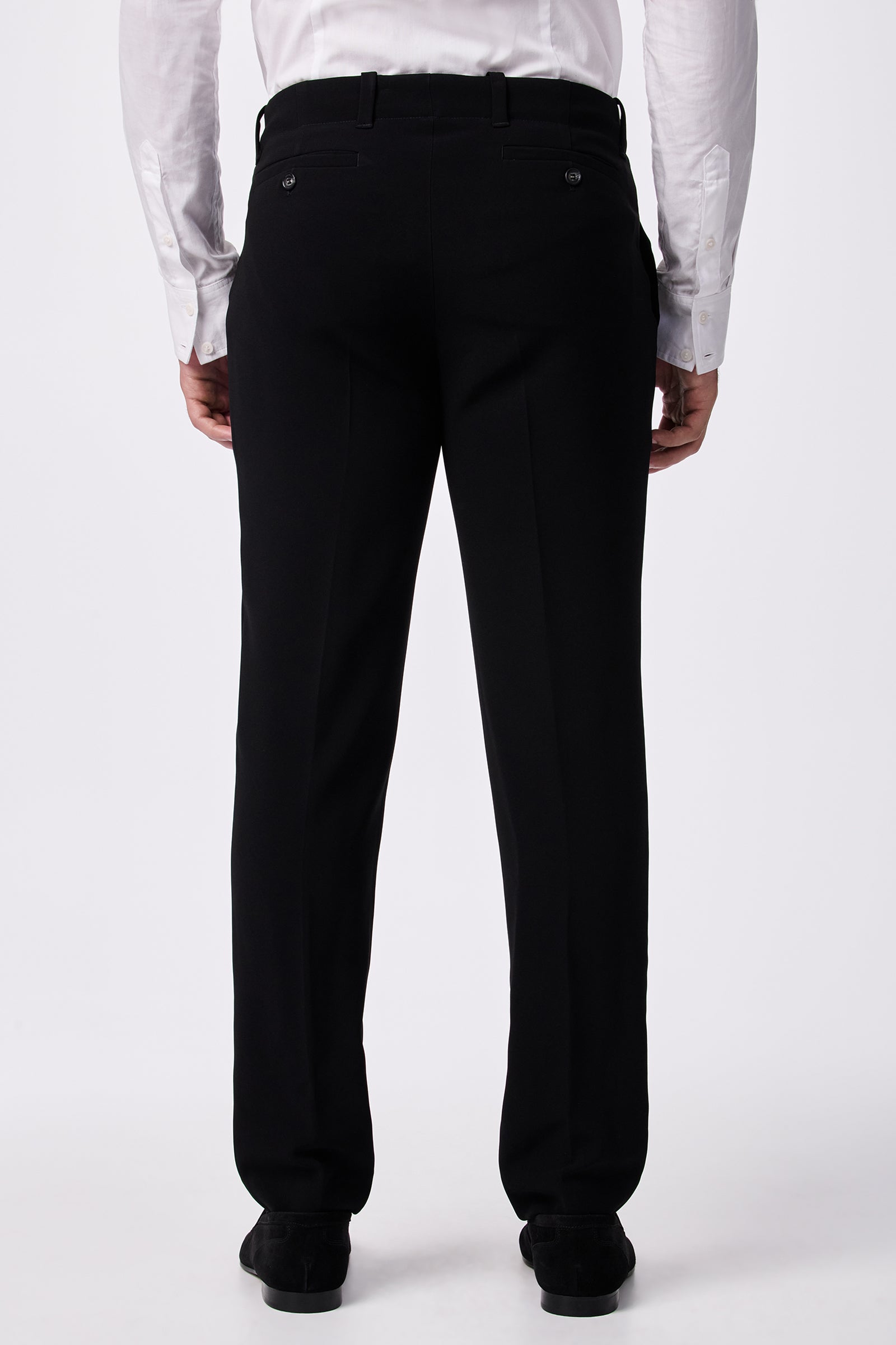 A person wearing a white dress shirt and the Alex Slim Trouser - Drapey Suiting in black is standing with their back to the camera, highlighting the back view of the trousers.
