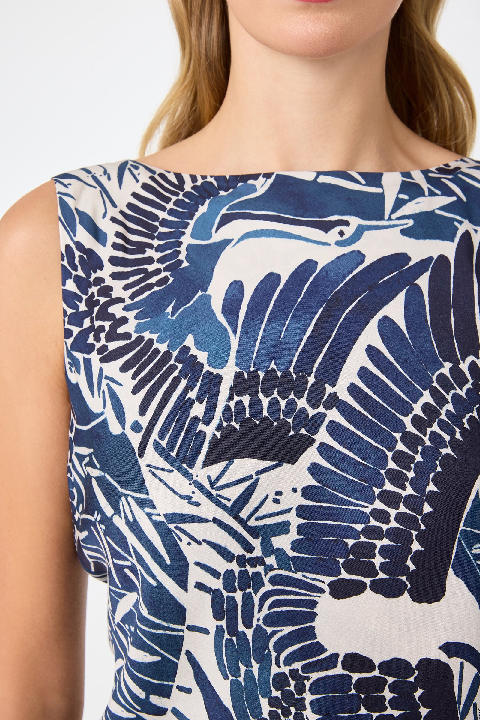 A woman wears the Hakuto Tie-Back Top - Tsuru, a sleeveless piece with bold blue and white abstract bird wing prints, shown from shoulders to mid-torso.