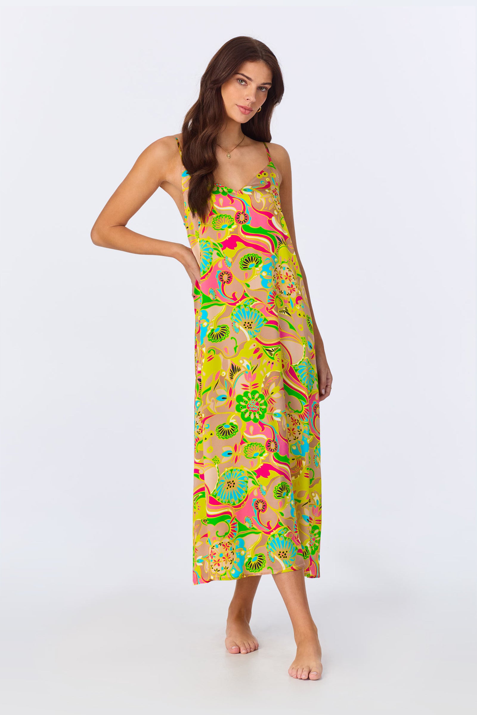 Woman with long brown hair wearing the TT Maxi Chemise Nightgown - Heritage Silk in multi, a sleeveless, ankle-length dress with a bright floral pattern, standing barefoot against a plain white background.