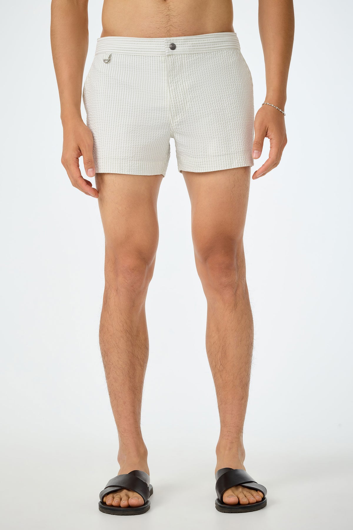 A man wearing the Chico Swim Trunk - Seersucker in Sand and black sandals stands against a plain white background. His upper body is not visible.