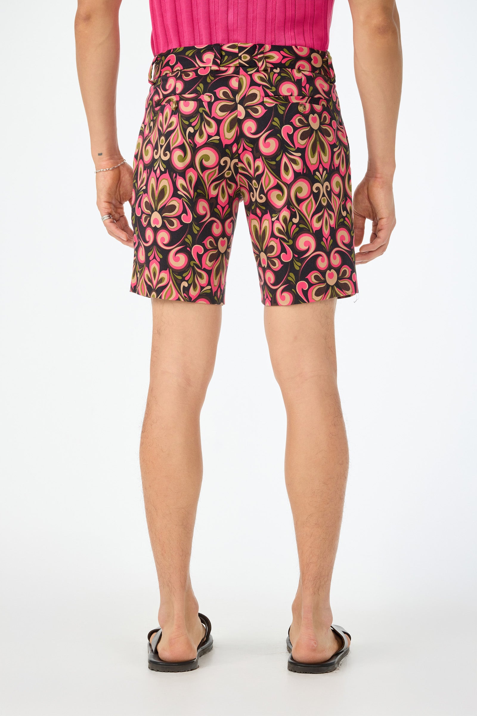 A person stands with their back to the camera against a white background, wearing a pink top, black flip-flops, and the Lawrence Short - Sanctuary Herringbone.