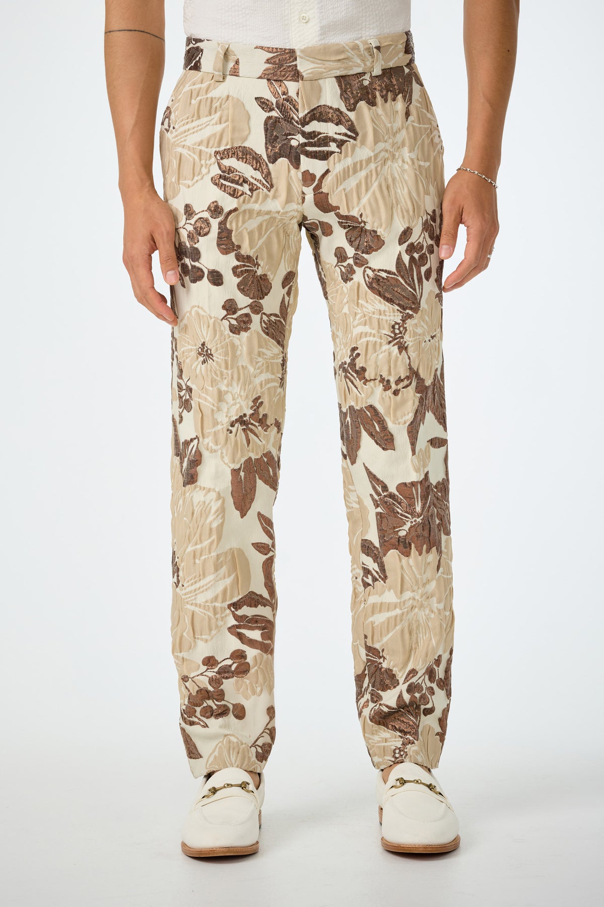 A person wearing the Clyde Slim Trouser in Daintree Jacquard, styled with a white shirt and white shoes, stands against a plain white background.