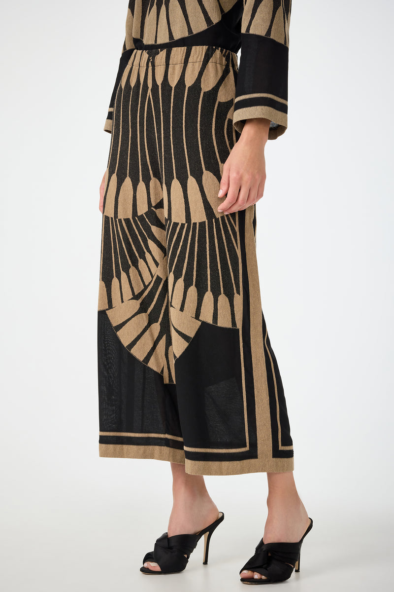 A person wearing Estella 2 Cropped Pants in Juniper Fil Coupe with a matching top and black high-heeled sandals, standing against a white background.