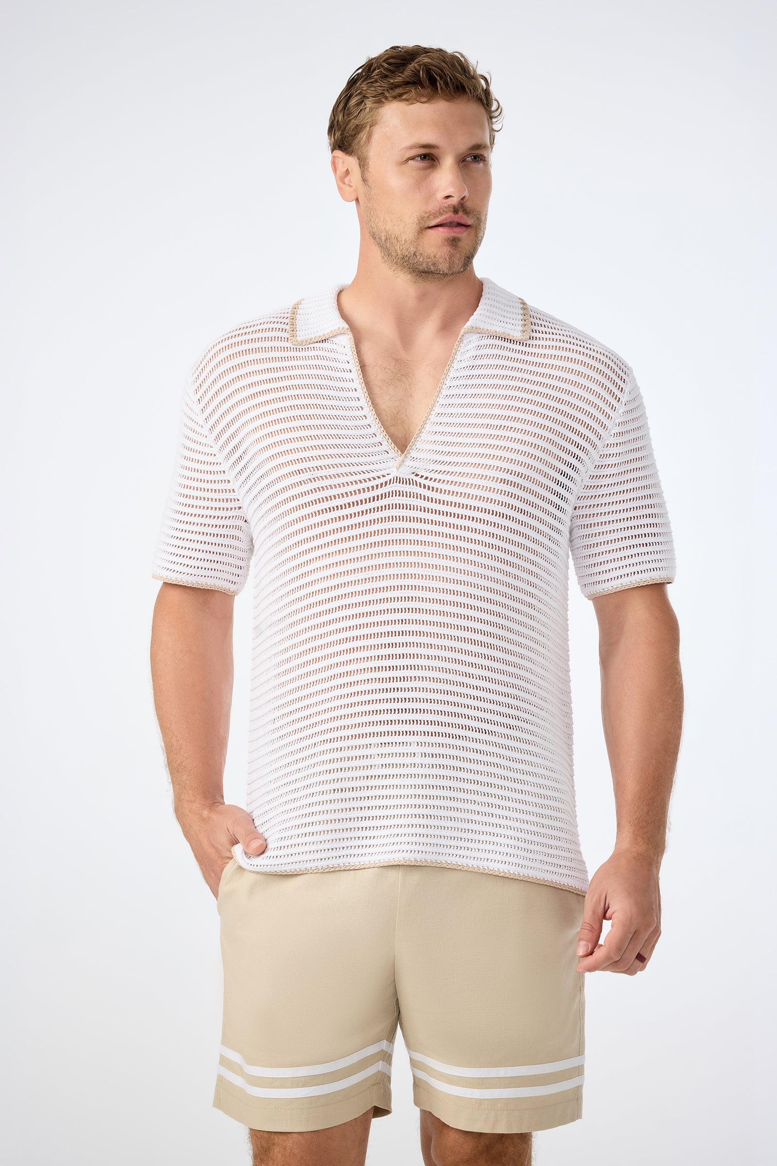 A man wearing the Triston Short-Sleeve Crochet Polo in Whitewash and beige shorts with white stripes, standing against a plain light background.