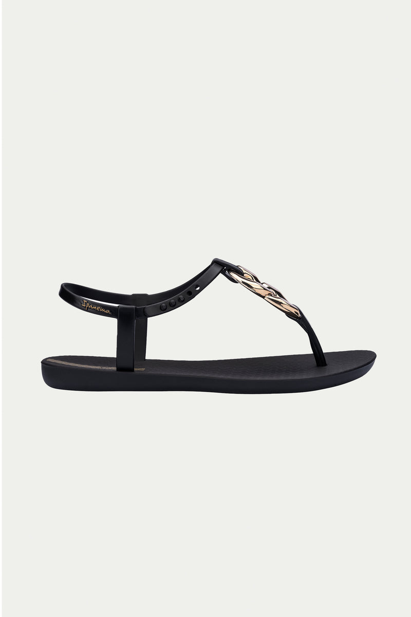 The Ipanema Class Connect Sandal in black features a T-strap design with a decorative metallic leaf detail on the upper strap, displayed against a light gray background.