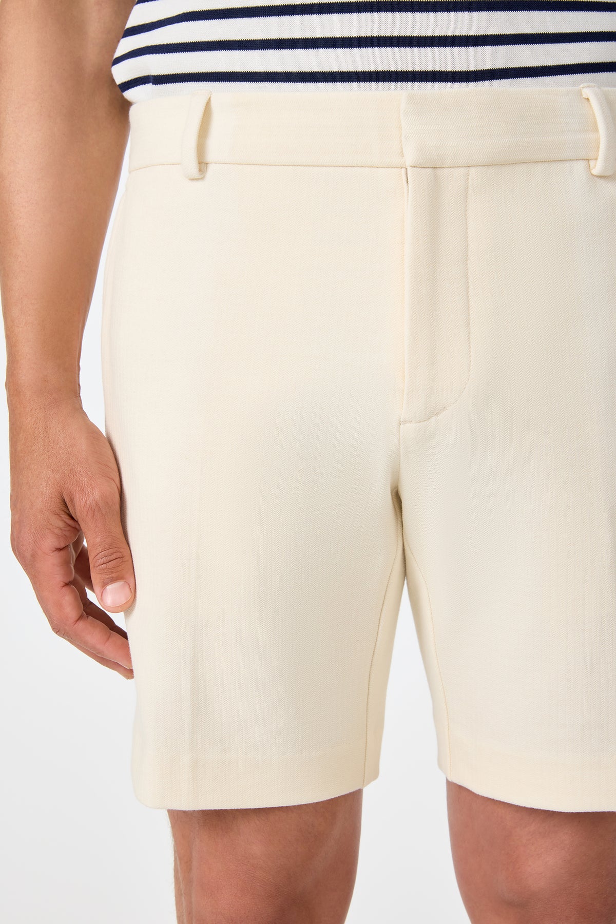 Shown from waist to mid-thigh, a person wears the Lawrence Short in ecru with one hand resting by their side and a navy and white striped top.