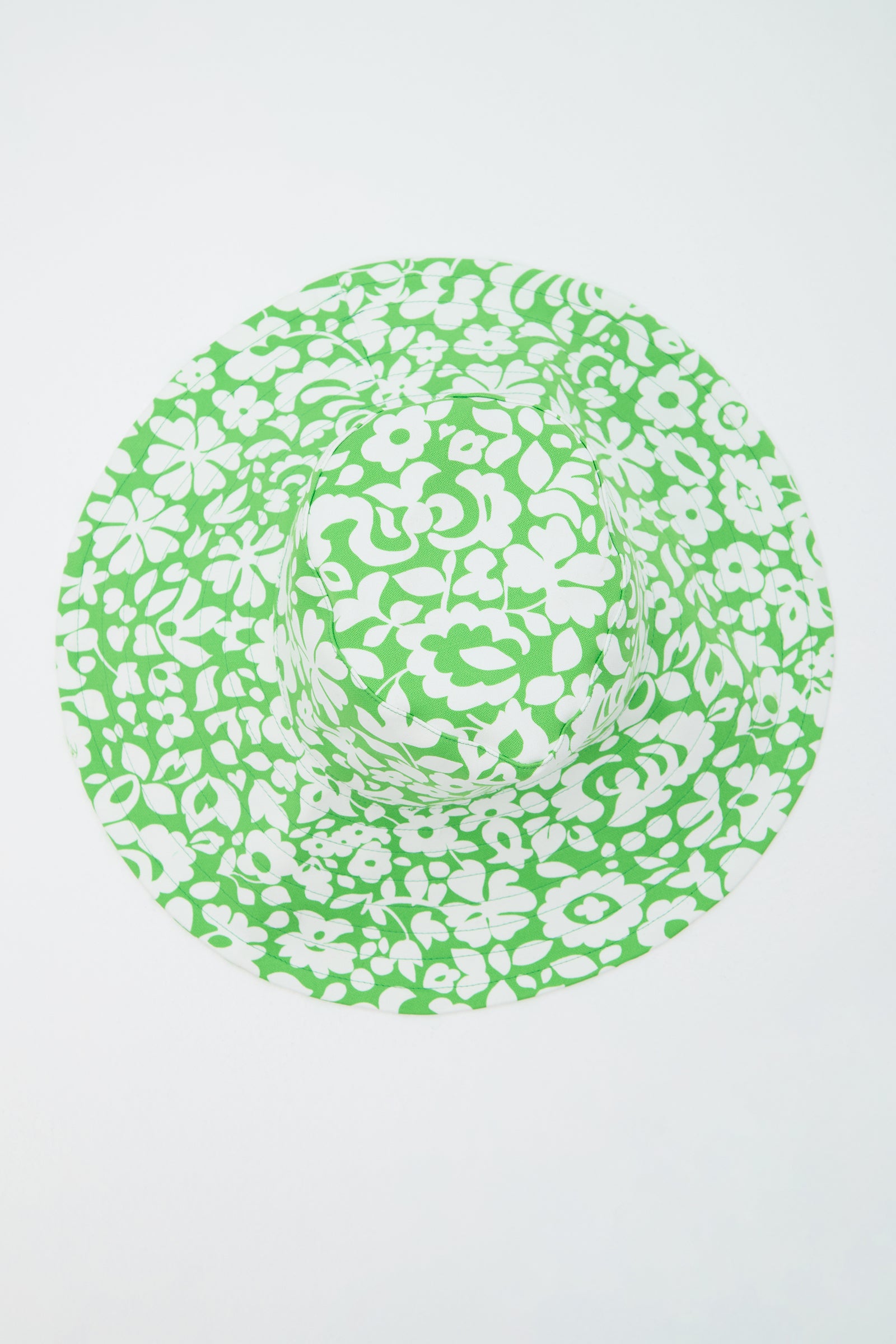 The Shade Packable Sun Hat - Poolside Gossip features a wide brim and a green and white floral pattern, shown from above on a plain white background.