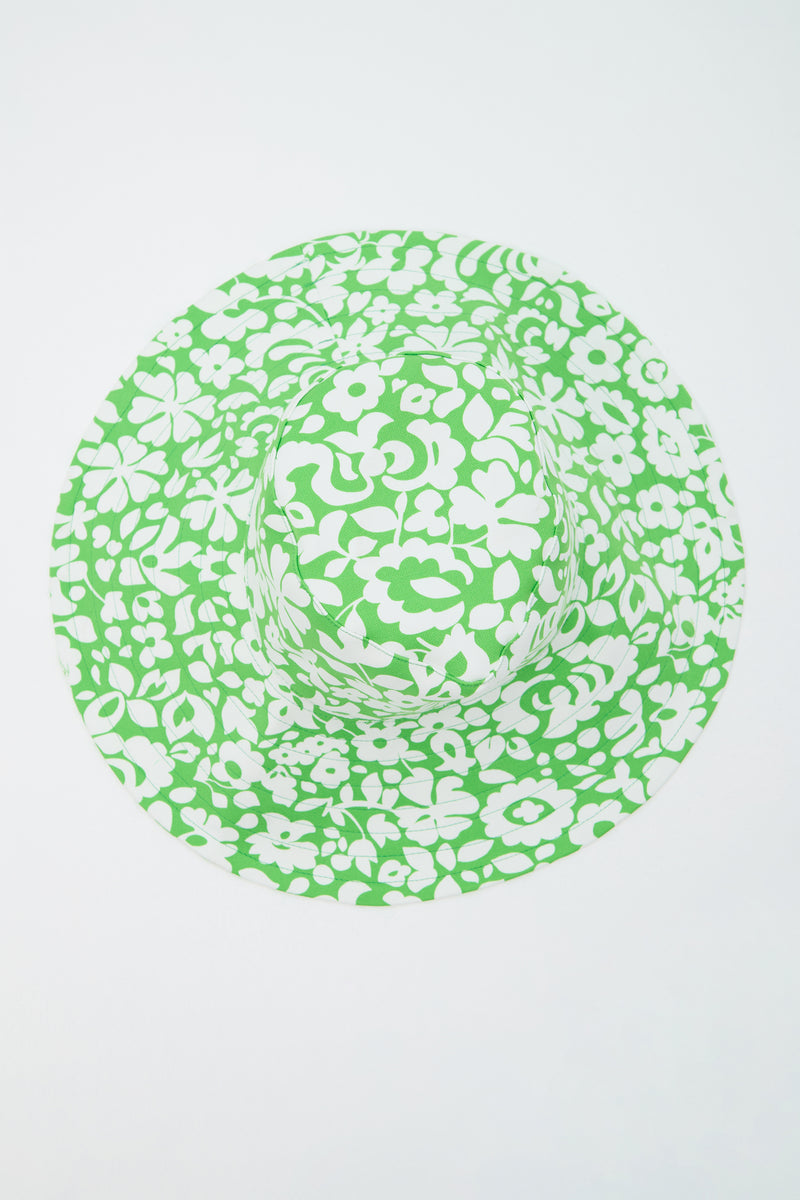 The Shade Packable Sun Hat - Poolside Gossip features a wide brim and a green and white floral pattern, shown from above on a plain white background.