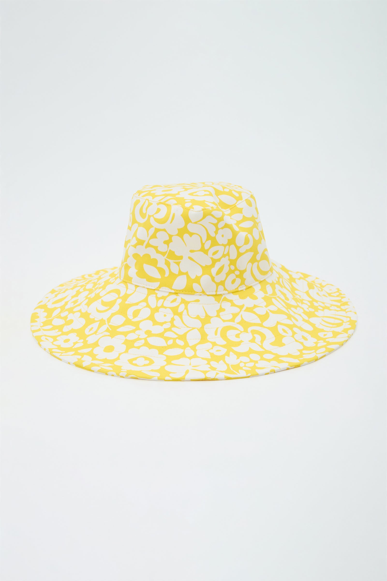 Yellow bucket hat with white floral pattern on a light gray background