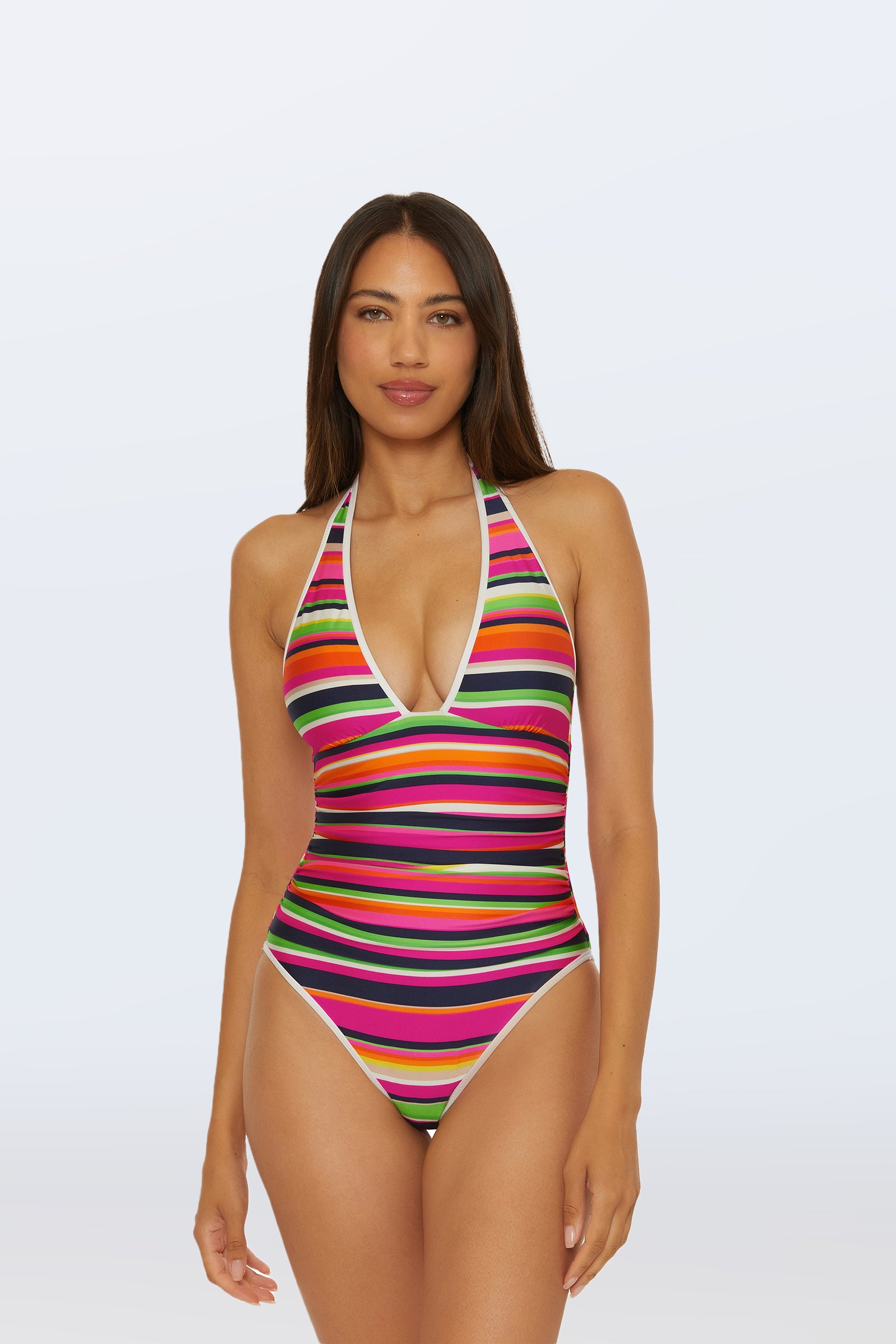 A woman models the Plunge One-Piece Swimsuit - Splash Stripe in Multi, featuring a deep V-neckline and bold stripes, as she poses confidently against a plain, light background.