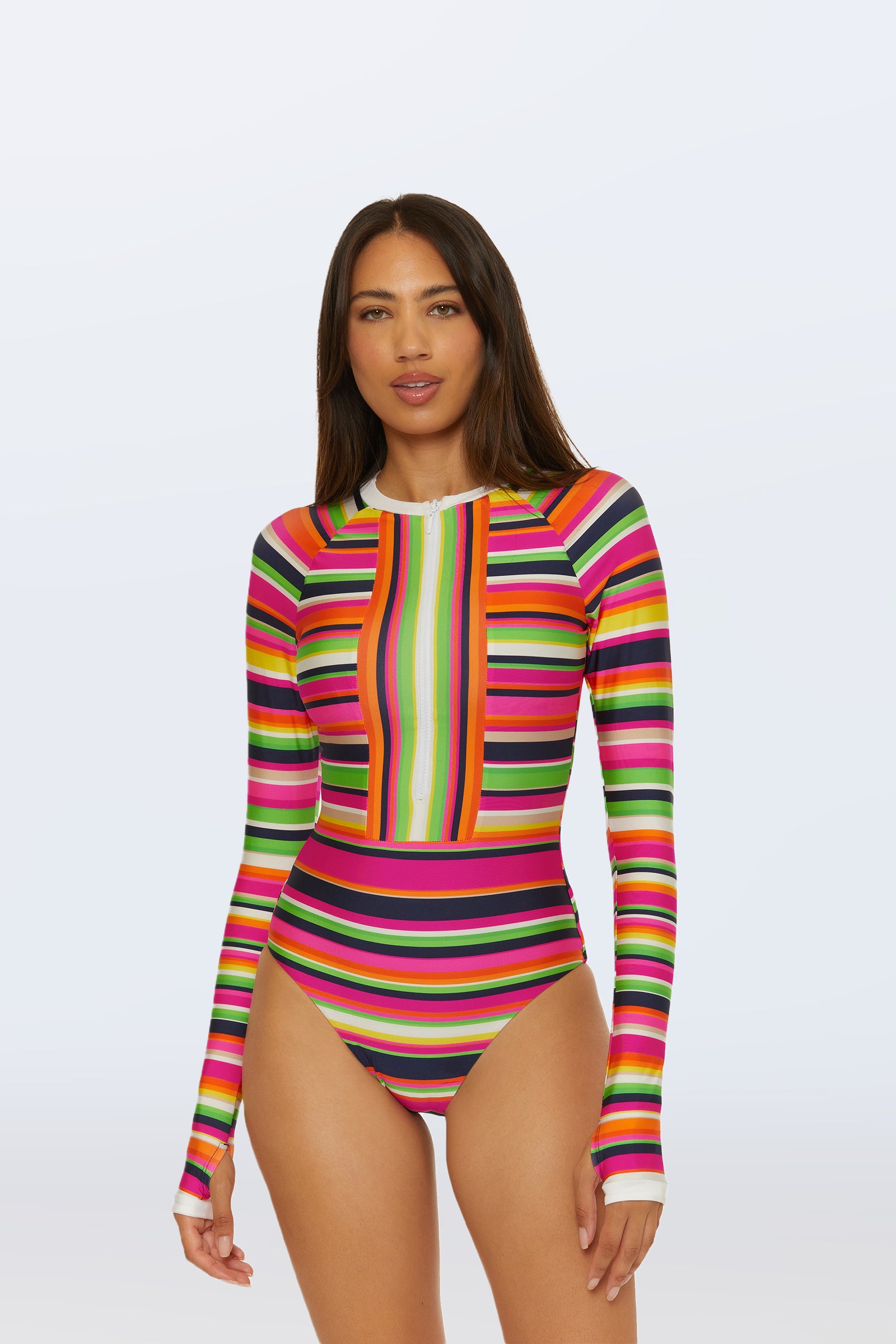 A woman stands against a light background wearing the Long-Sleeve Paddle Suit - Splash Stripe in Multi, featuring a high neck and colorful pink, green, orange, yellow, and black stripes.