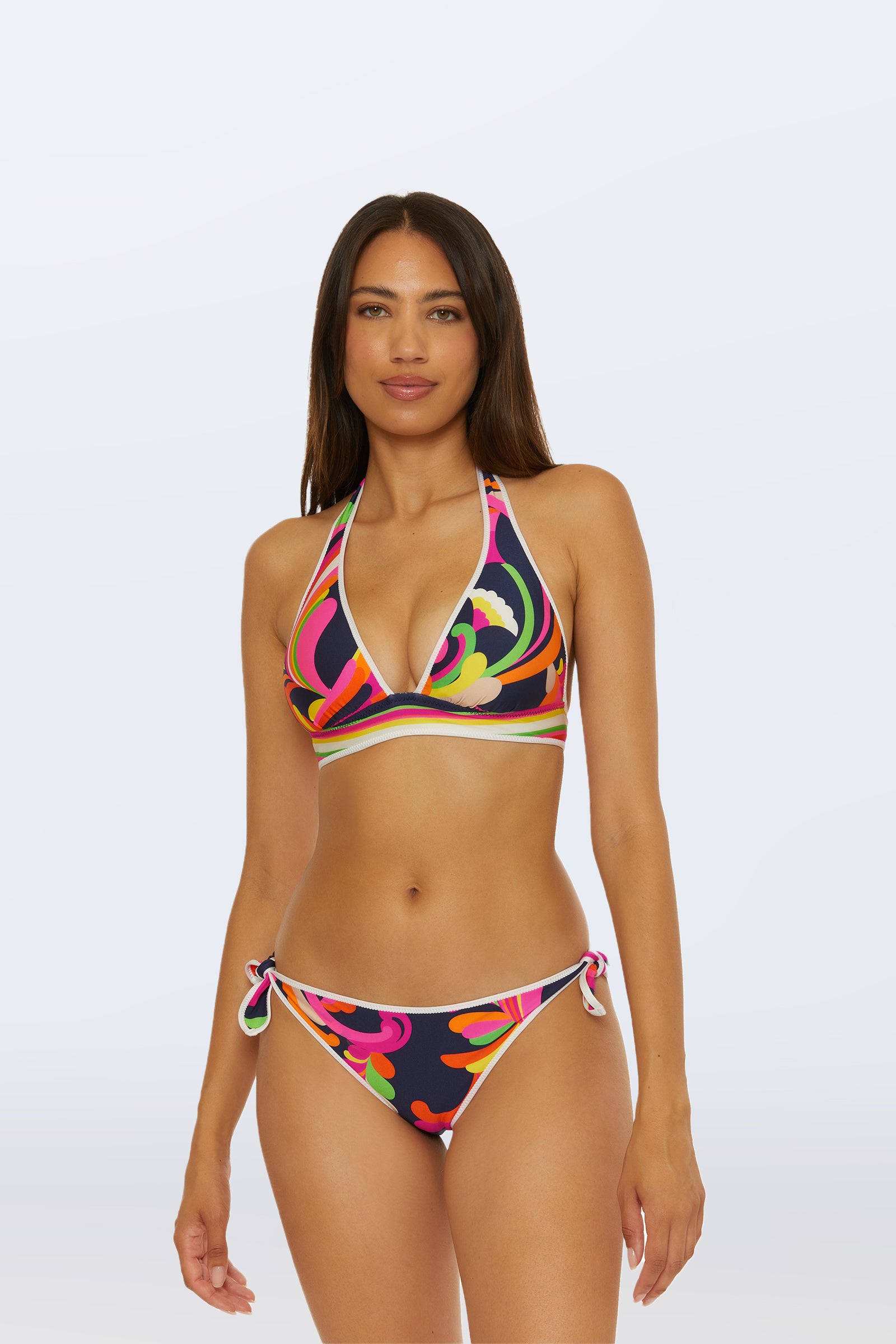 A woman poses confidently against a plain light background, wearing the Reversible Halter Swim Top in Splash Stripe with side-tie bikini bottoms.