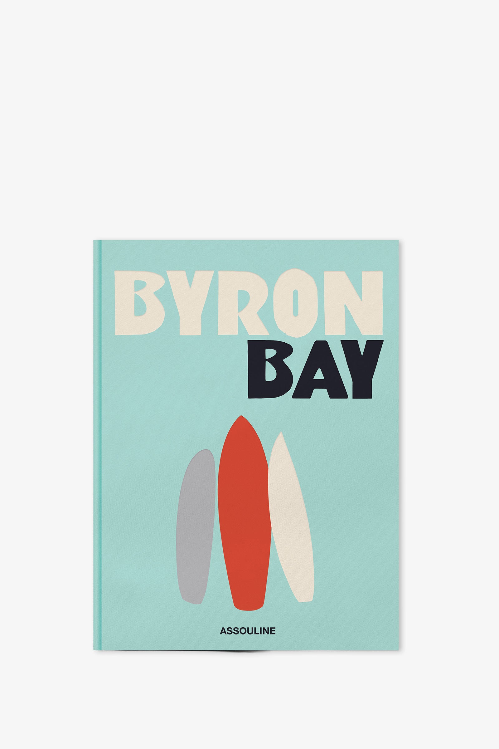 A book titled ASSOULINE BYRON BAY features three surfboards illustrated on a light blue cover, with the publisher's name, Assouline, printed at the bottom.