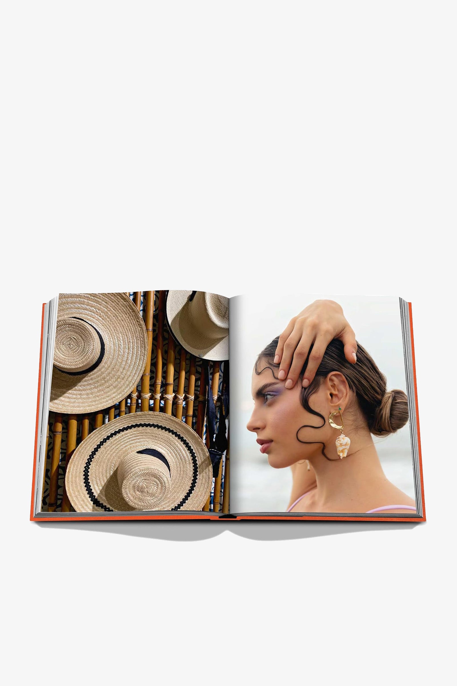 The Assouline Cartagena Grace Book features an open spread with straw hats displayed on the left page and a woman wearing earrings and styled hair, touching her head, on the right page—both set against light backgrounds.