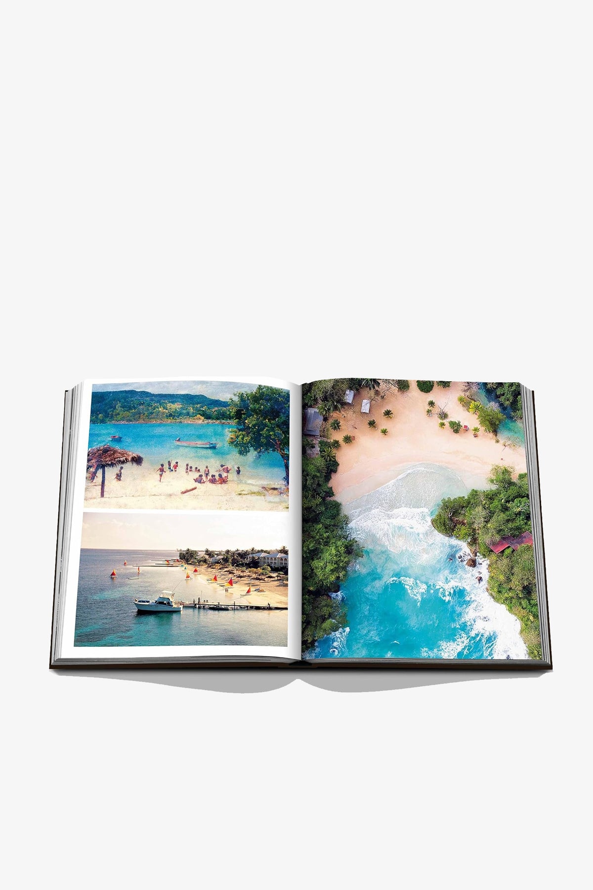 An open Assouline Jamaica Vibes photo book displays tropical beach scenes with clear blue water, lush greenery, and people relaxing by the shore. The vivid images capture vibrant, sunny coastal landscapes.