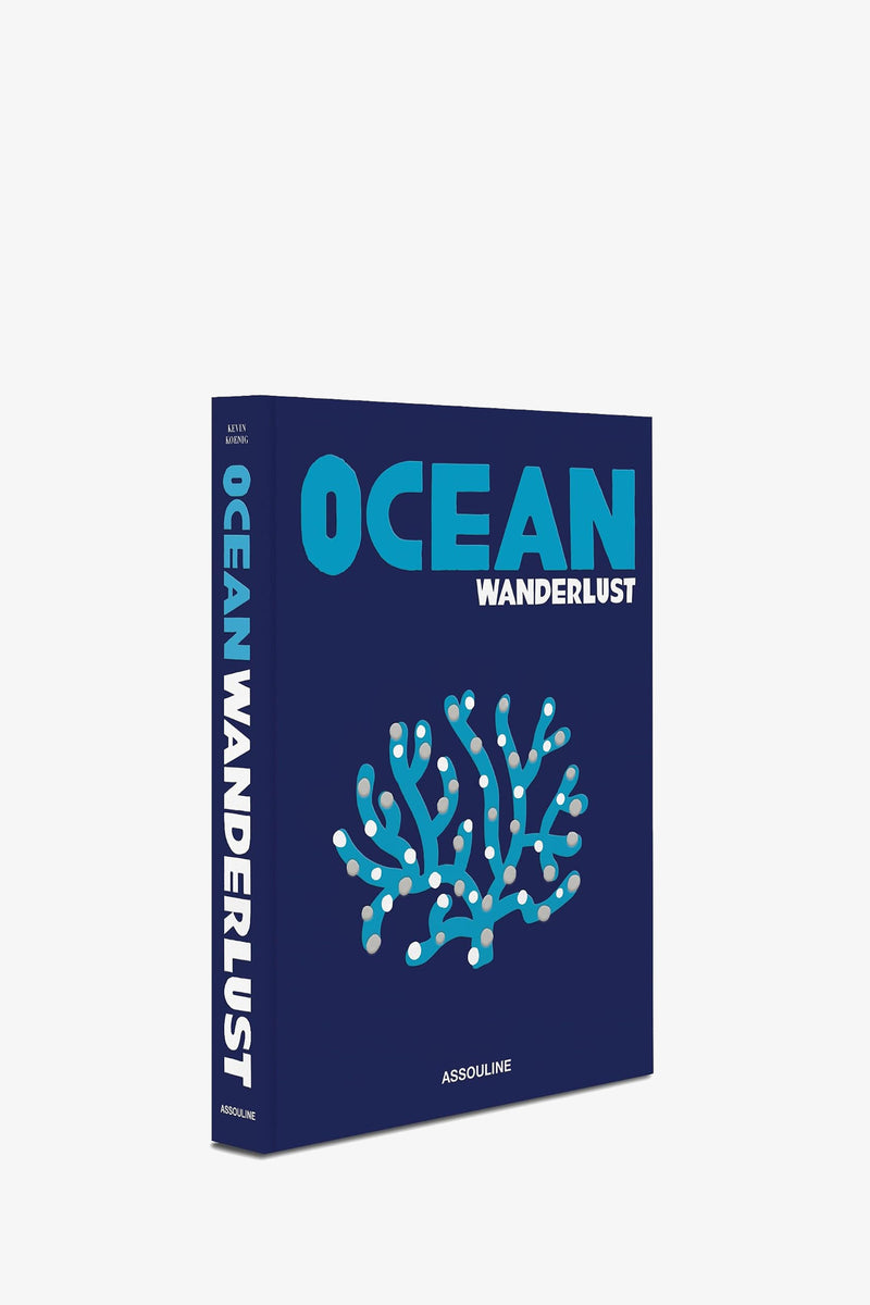 Assouline Ocean Wanderlust is a book with a blue cover displaying an illustration of coral. The title appears in large blue and white letters on both the cover and spine, with the publisher Assouline printed at the bottom.
