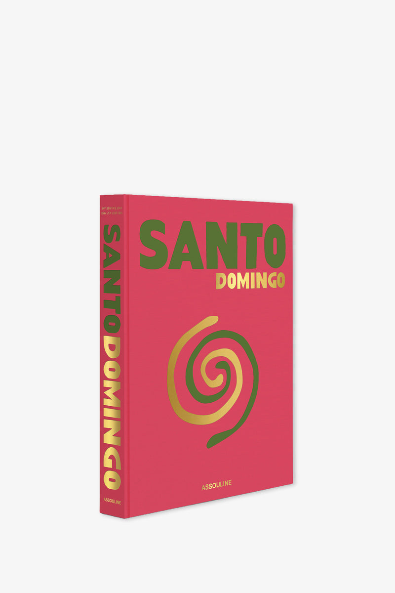 The Assouline Santo Domingo Book features a red cover with gold and green lettering and a yellow spiral design. It is displayed standing upright against a white background.