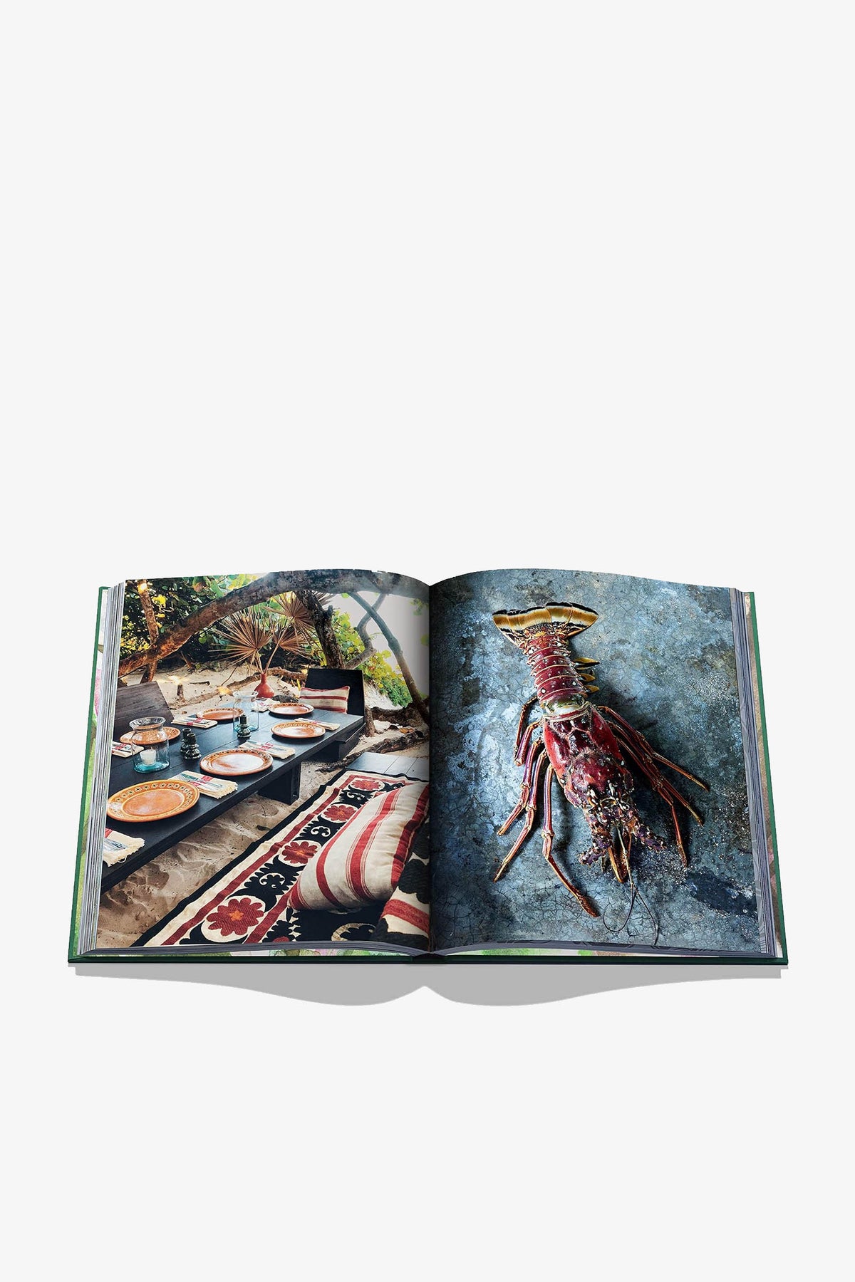 An open Assouline Tulum Gypset Book displays a coastal dining scene on the left page and a spiny lobster on a textured surface on the right page.