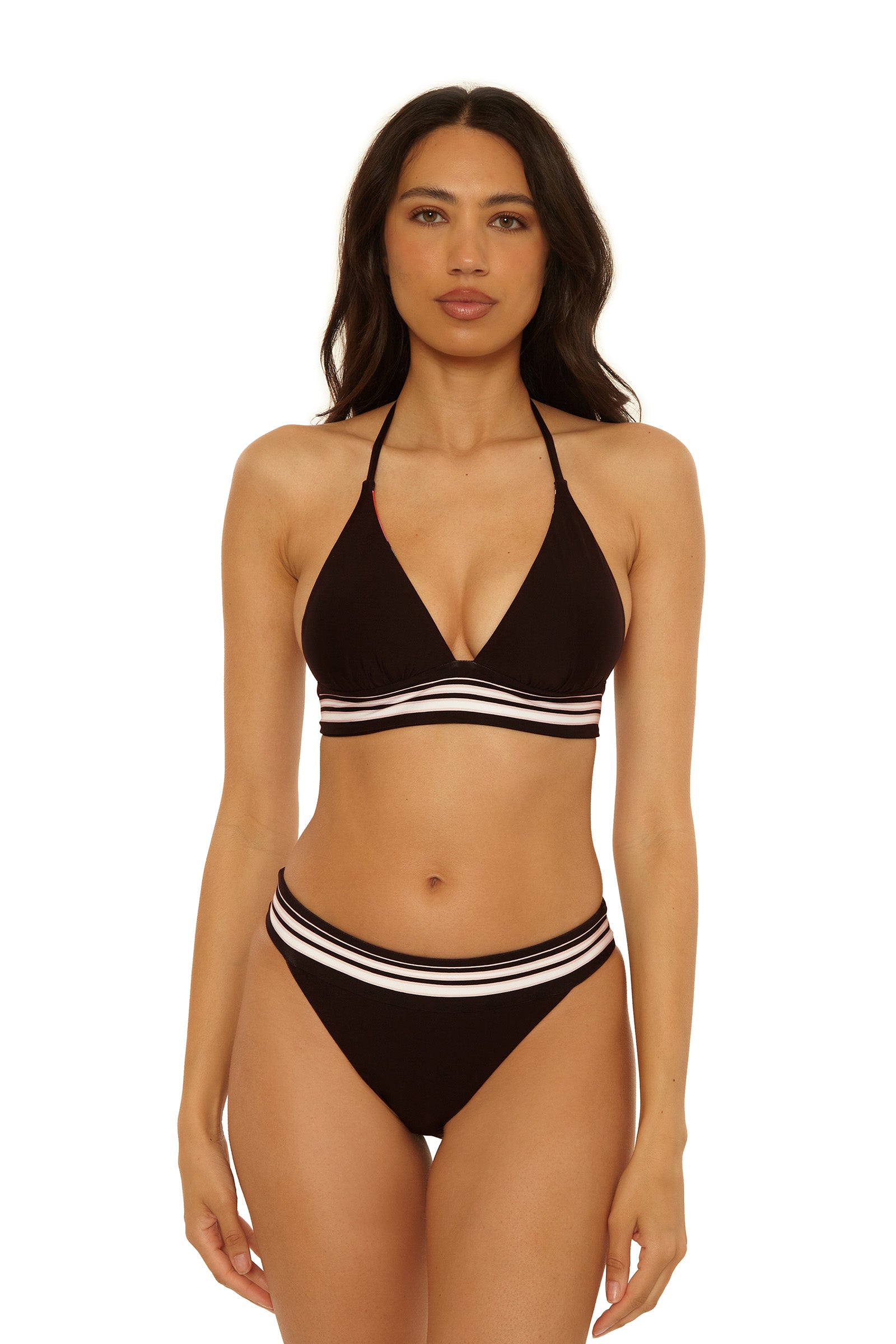 A woman with long dark hair wears the Reversible Halter Swim Top - Bougainvillea, a black bikini top with white and pink striped bands. She stands facing forward against a plain white background.