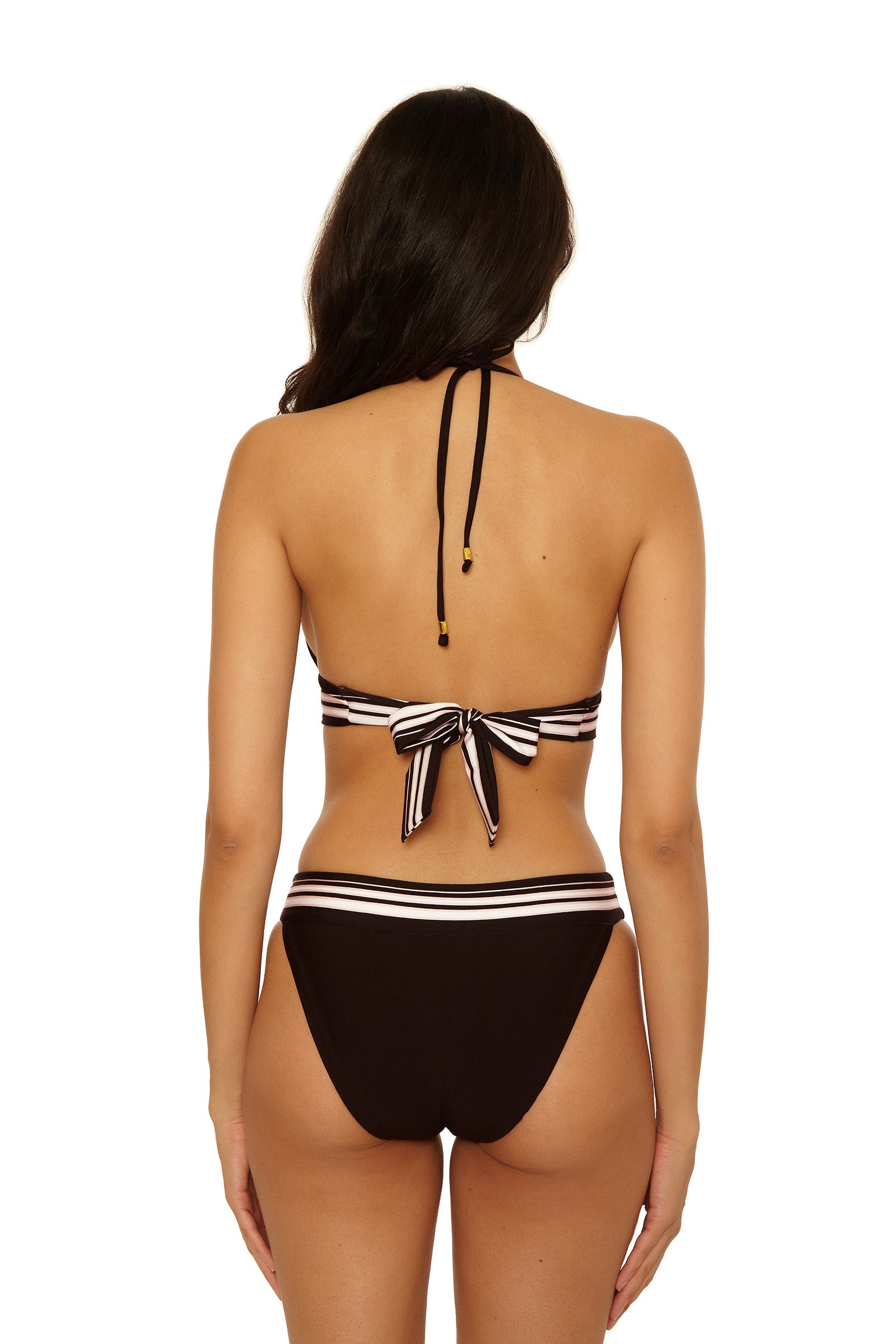 A woman with long dark hair models the Reversible Halter Swim Top - Bougainvillea, a black bikini top with white and pink striped trim. Shown from the back, it ties around her neck and back in a bow.