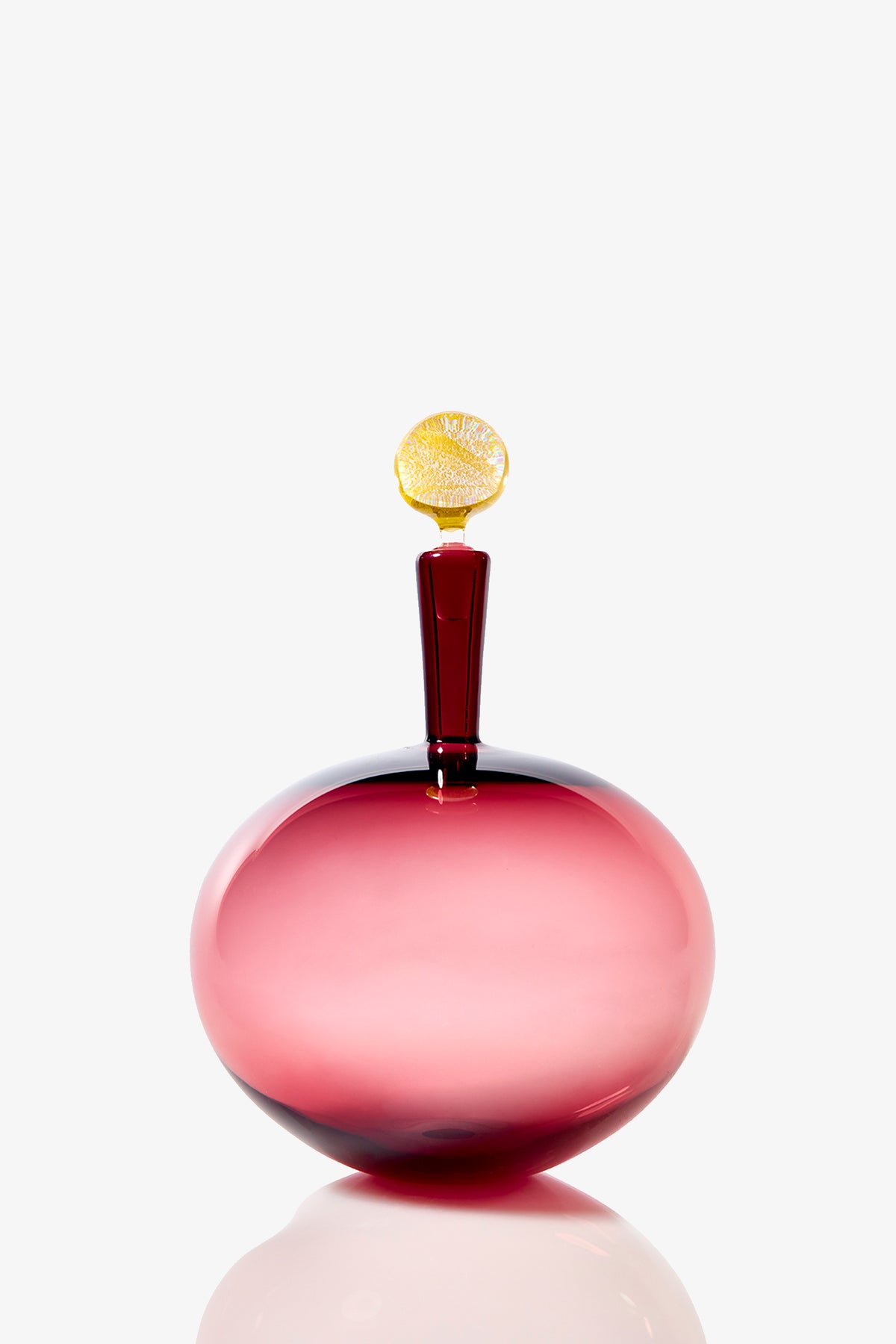 The Carmella Barware Low Round is a glossy pink glass bottle with a short neck and a yellow stopper shaped like a lemon slice, displayed against a plain white background.