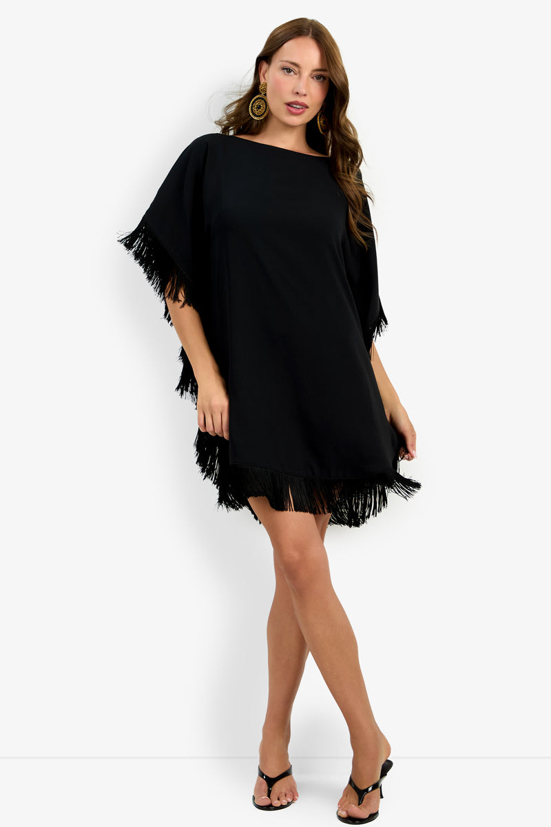 A woman models the Mini Neena Fringe Dress, posing with one hand in her hair and the other by her side against a plain white background.