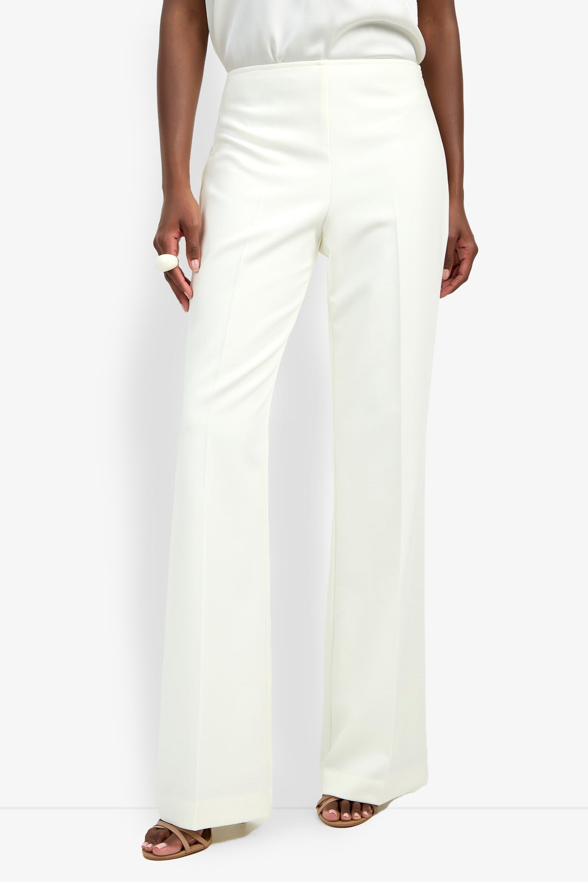 Someone models the CHIMAYO 2 PANT—high-waisted, white, wide-leg dress pants made from a soft polyester-viscose-elastane blend—styled with open-toe sandals against a plain white background.