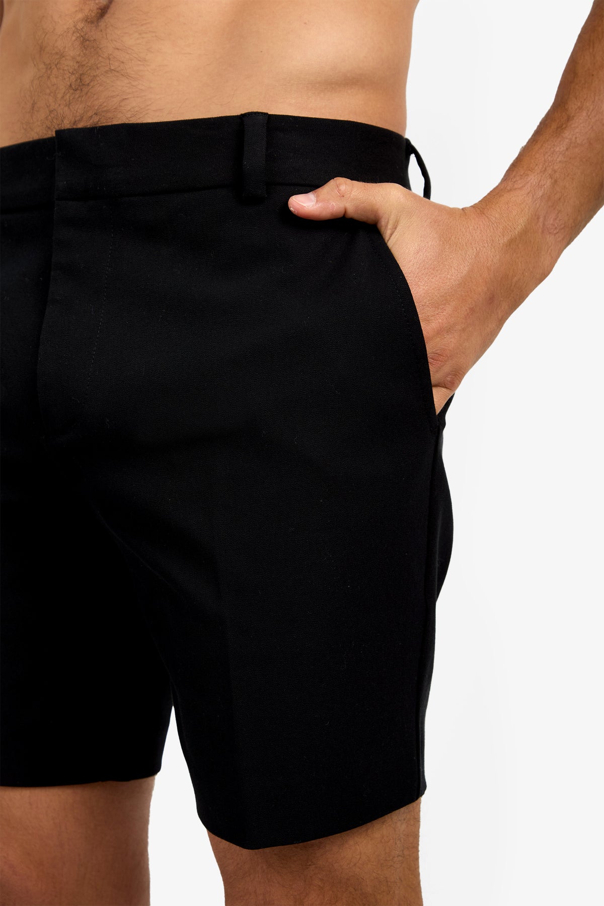 A person models the Lawrence Short in black, with their right hand in the pocket, highlighting a close-up of the shorts and part of their bare torso and arm against a white background.